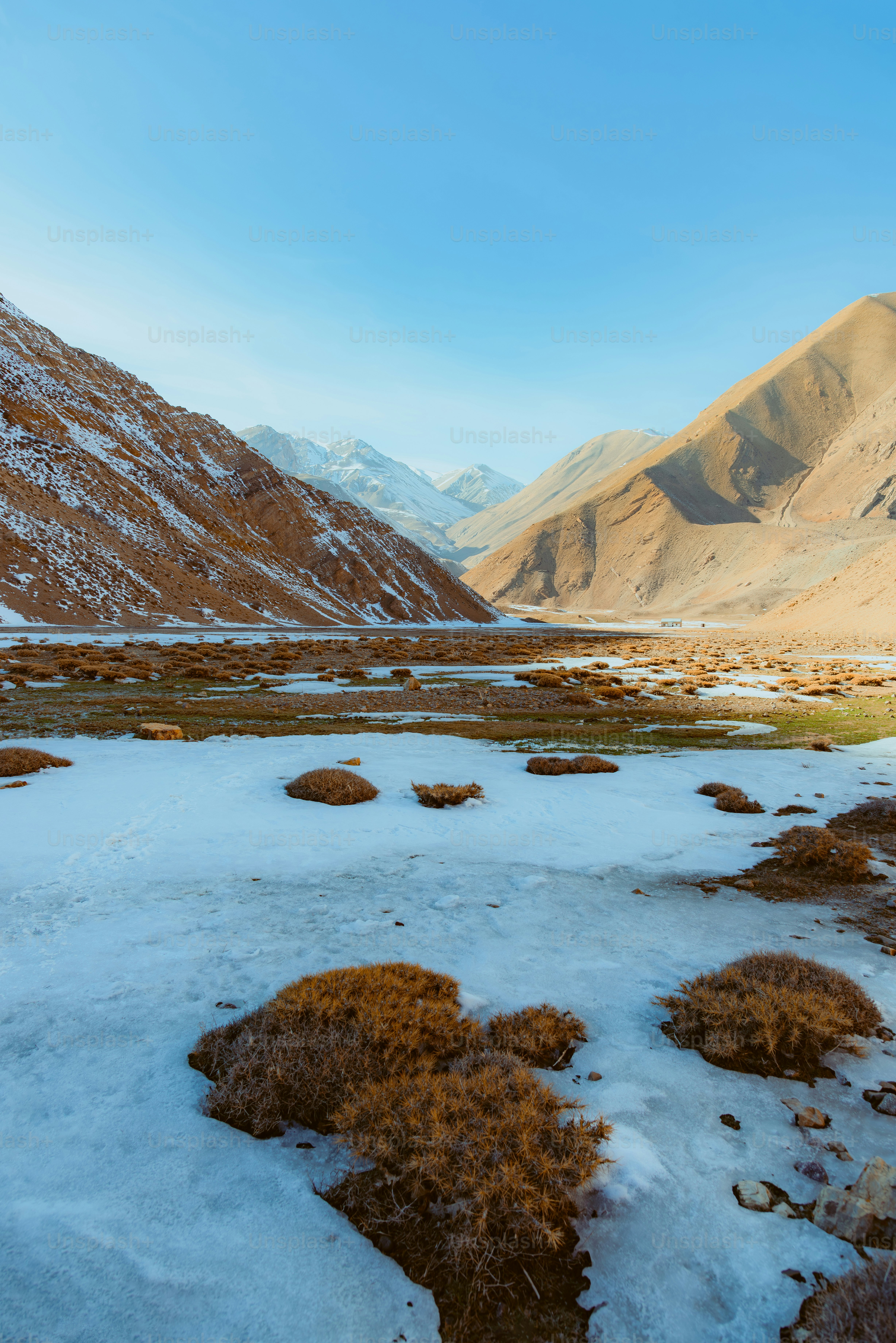 Snowy valley with mountains under a clear blue sky