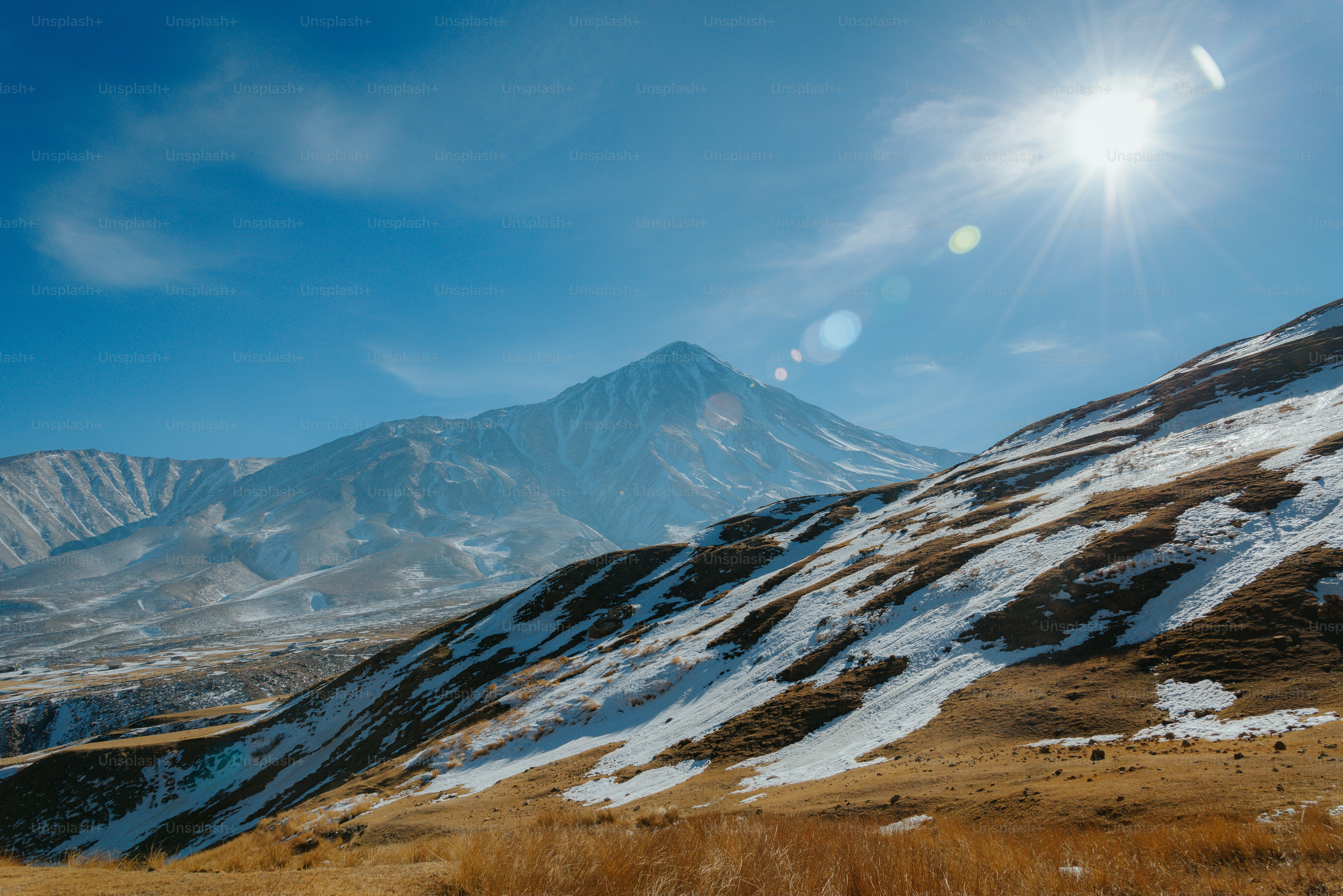 Montanhas cobertas de neve sob um céu ensolarado e brilhante.