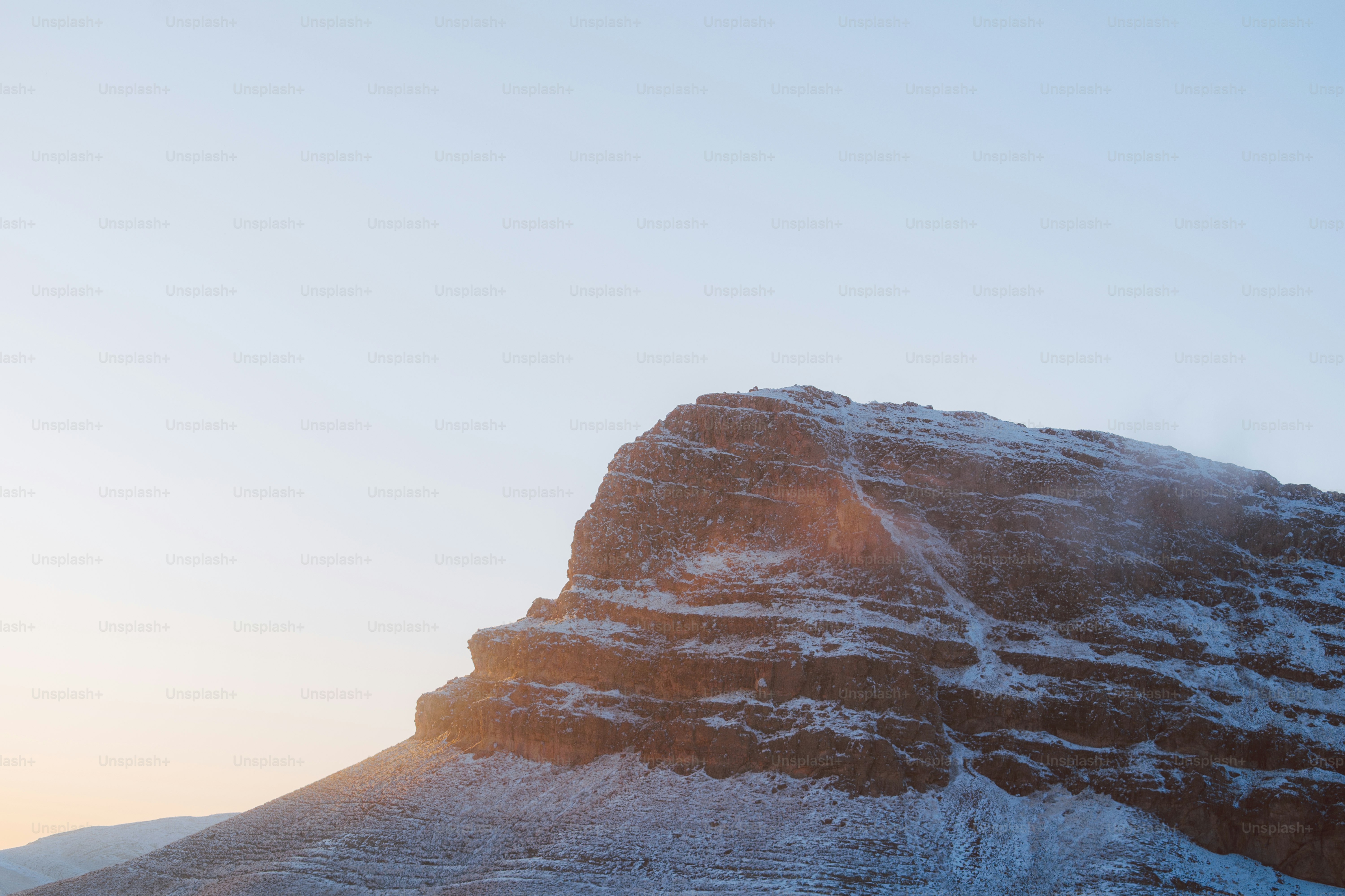 Snow-covered mountain peak at sunrise with soft sunlight.