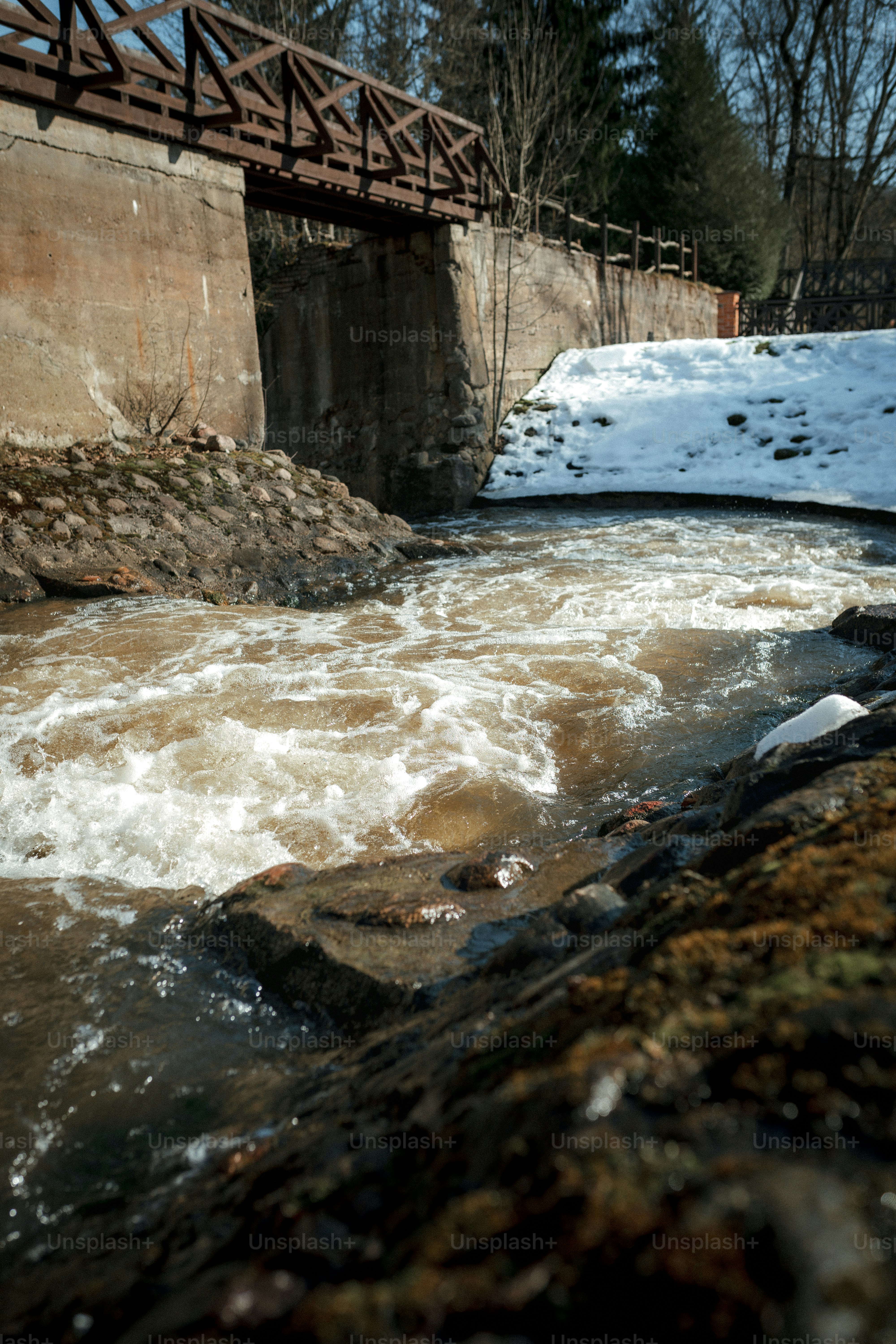 Sungai yang mengalir deras melewati jembatan kayu.