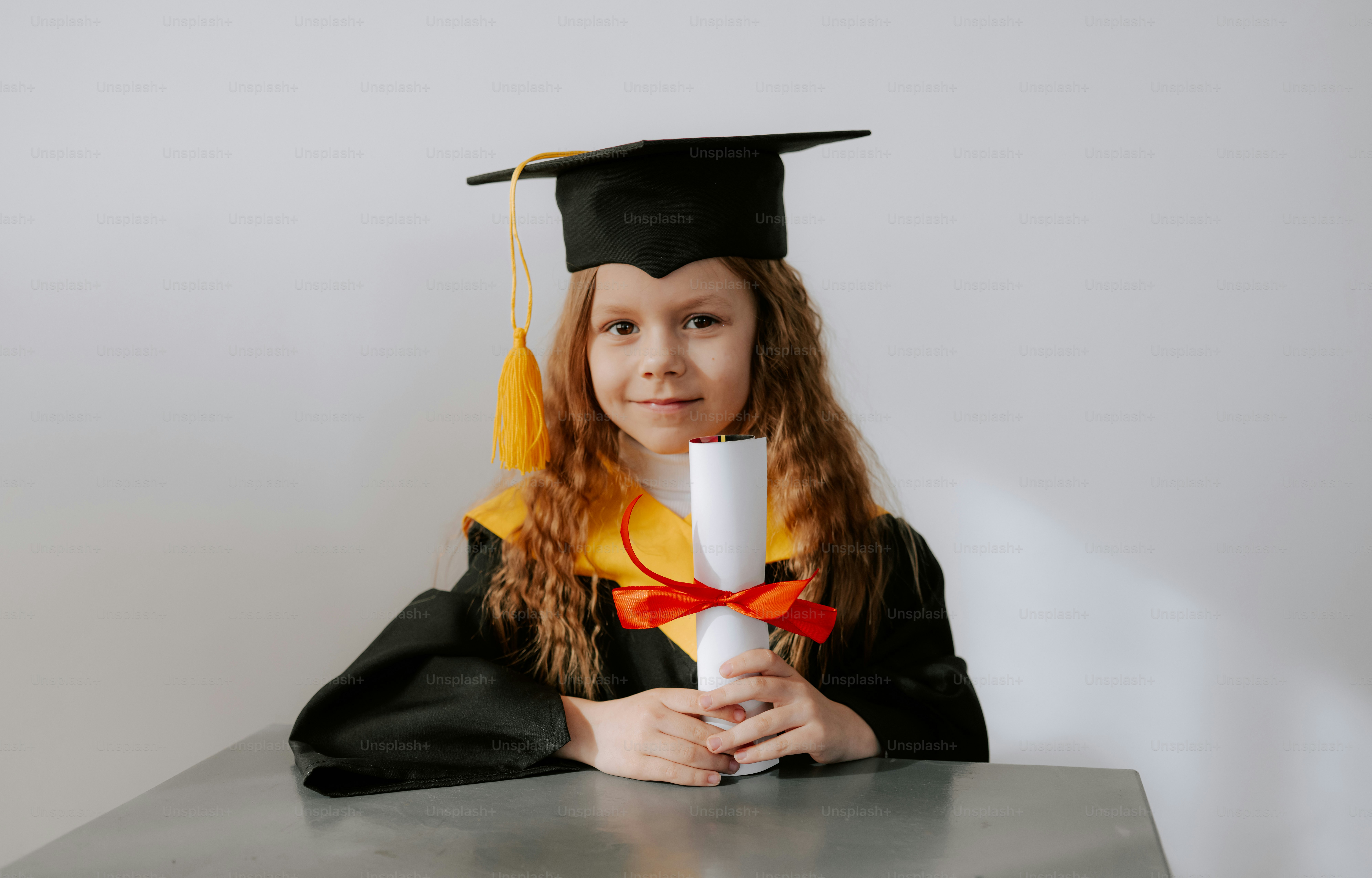 A young girl in graduation attire holds a diploma.