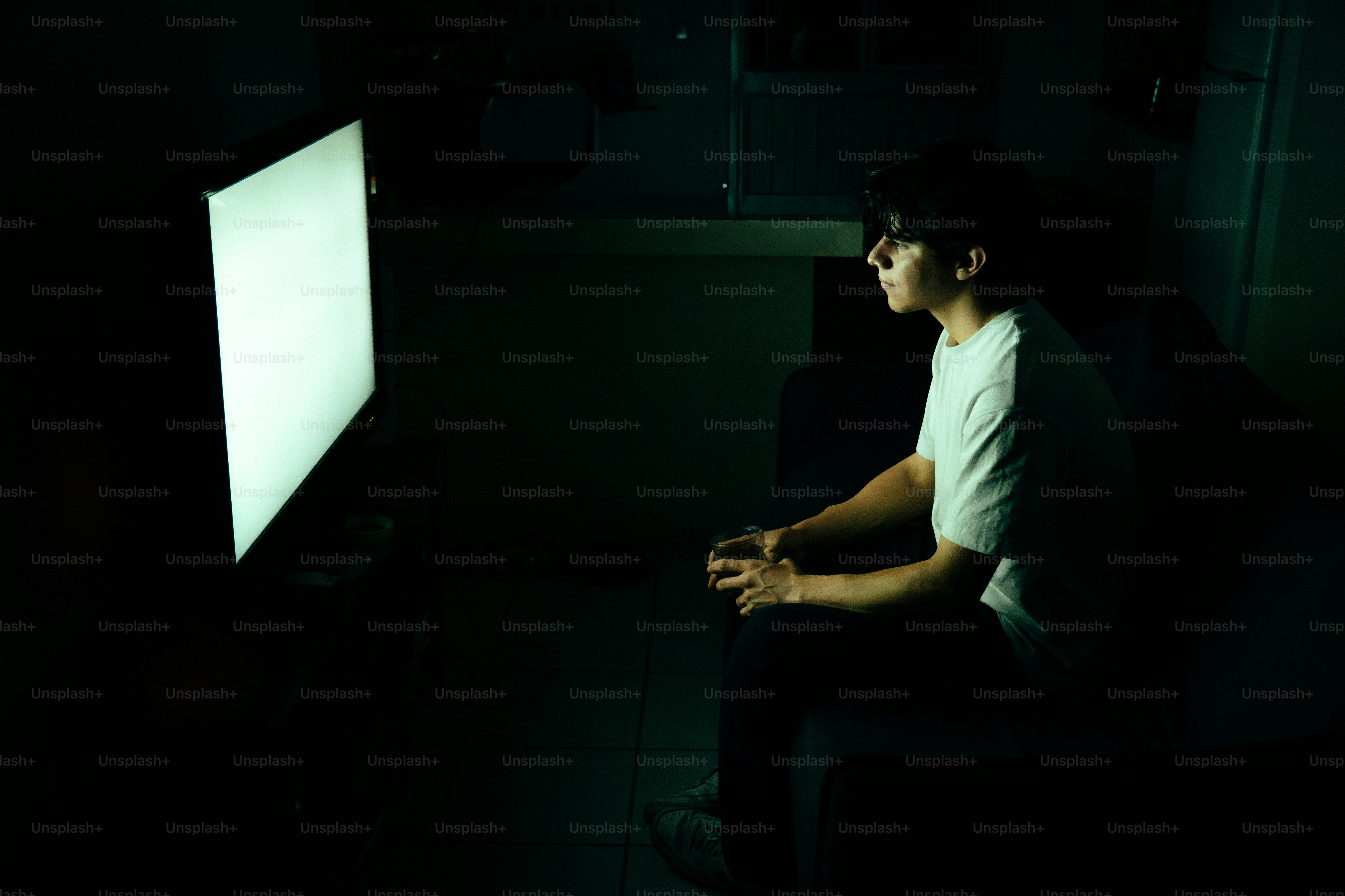 Young man illuminated by phone screen in dark room photo – Technology ...