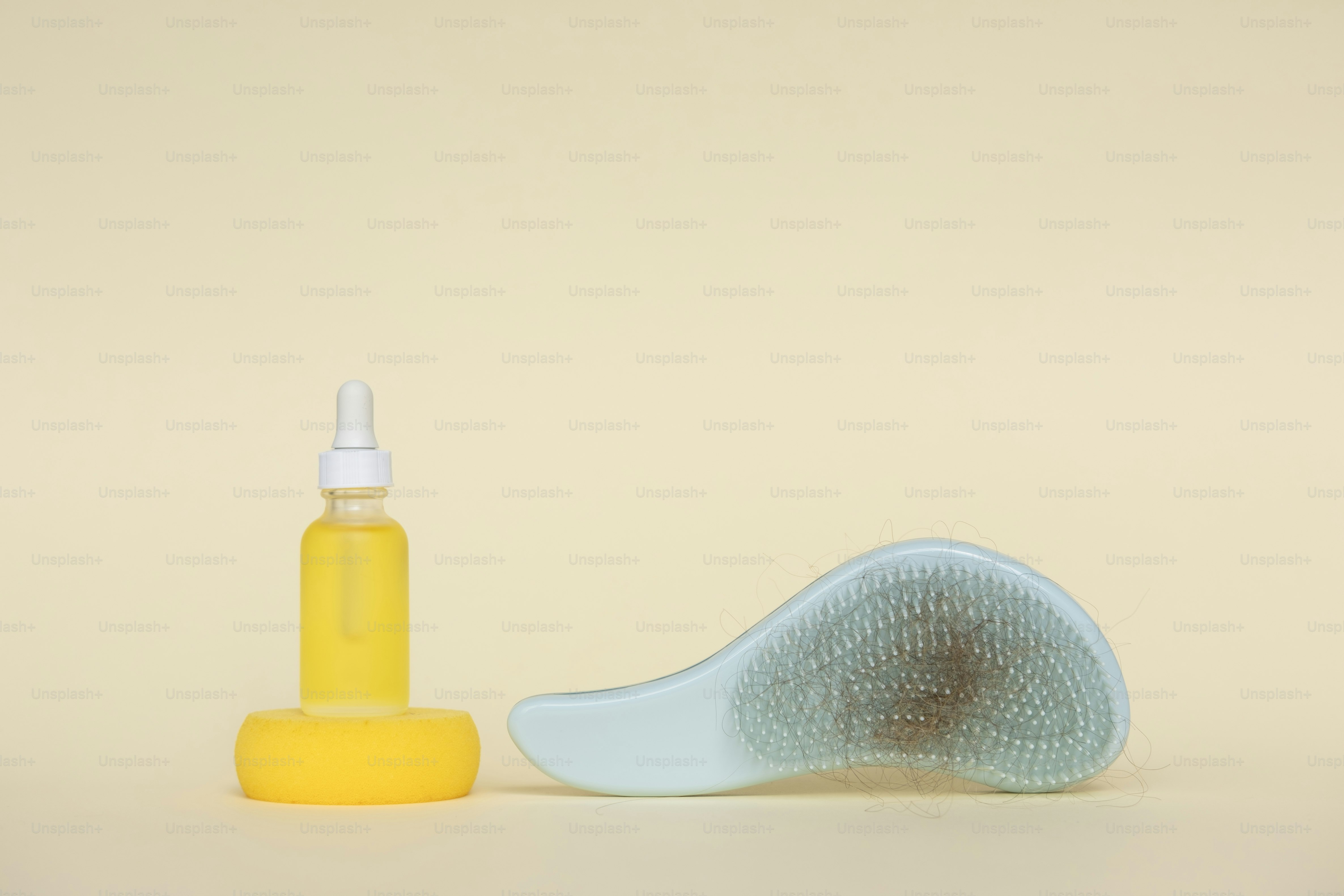 A bottle of yellow oil and a hairbrush