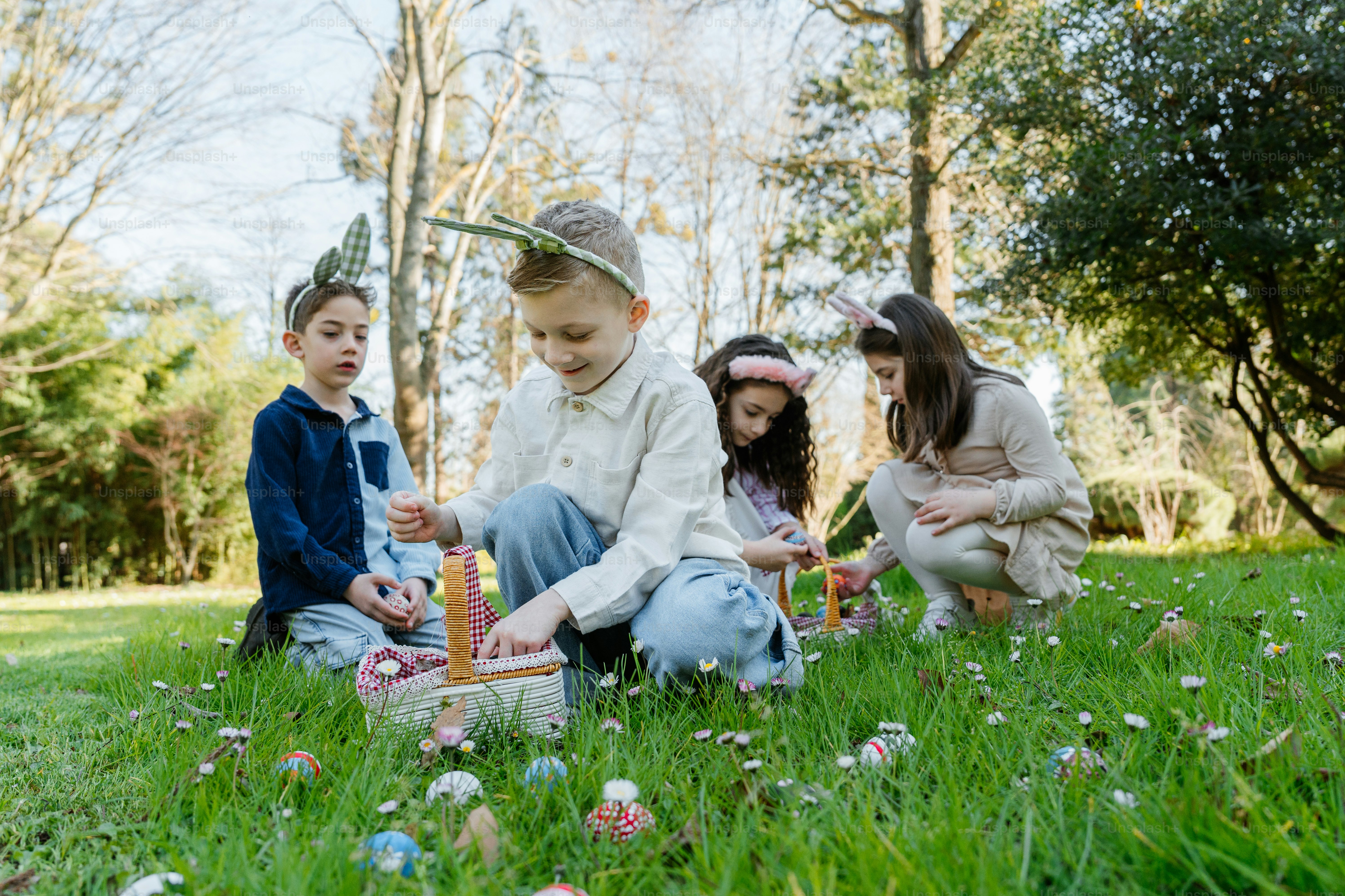 부활절 바구니를 든 아이들이 공원에서 달걀을 찾는다.