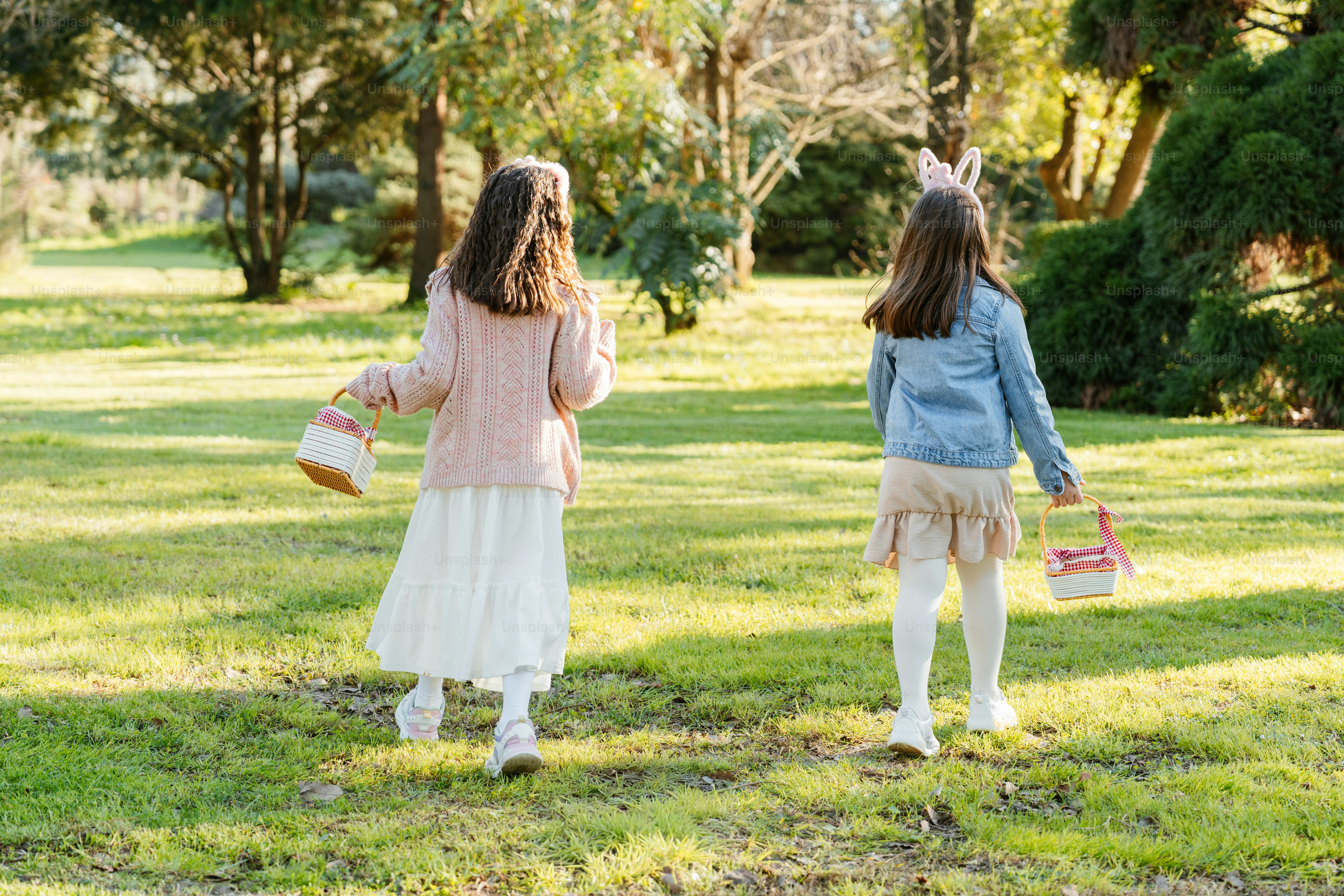 부활절 바구니를 든 두 소녀가 공원을 걷고 있다