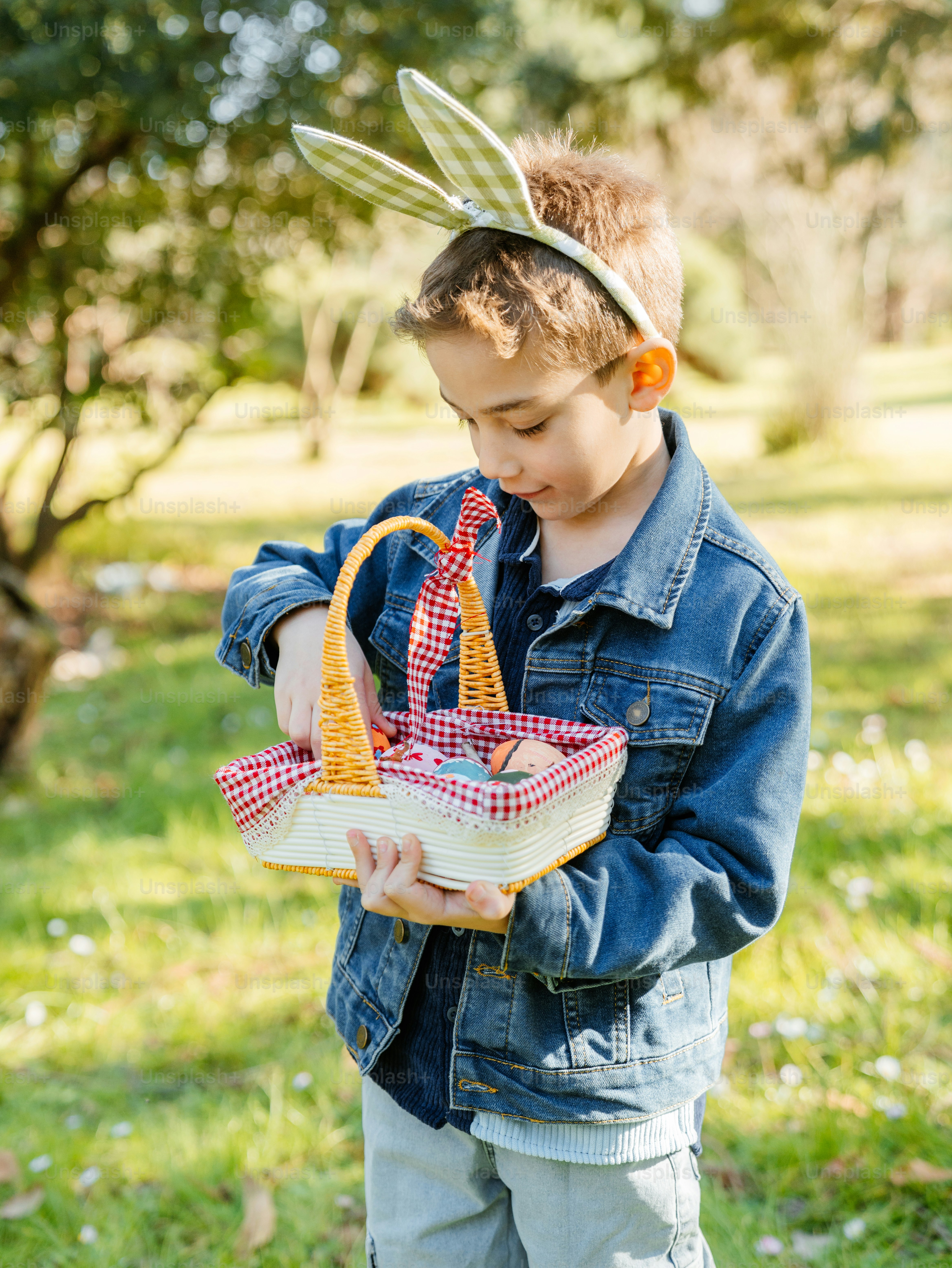 부활절 바구니와 토끼 귀를 가진 소년이 아래를 내려다본다