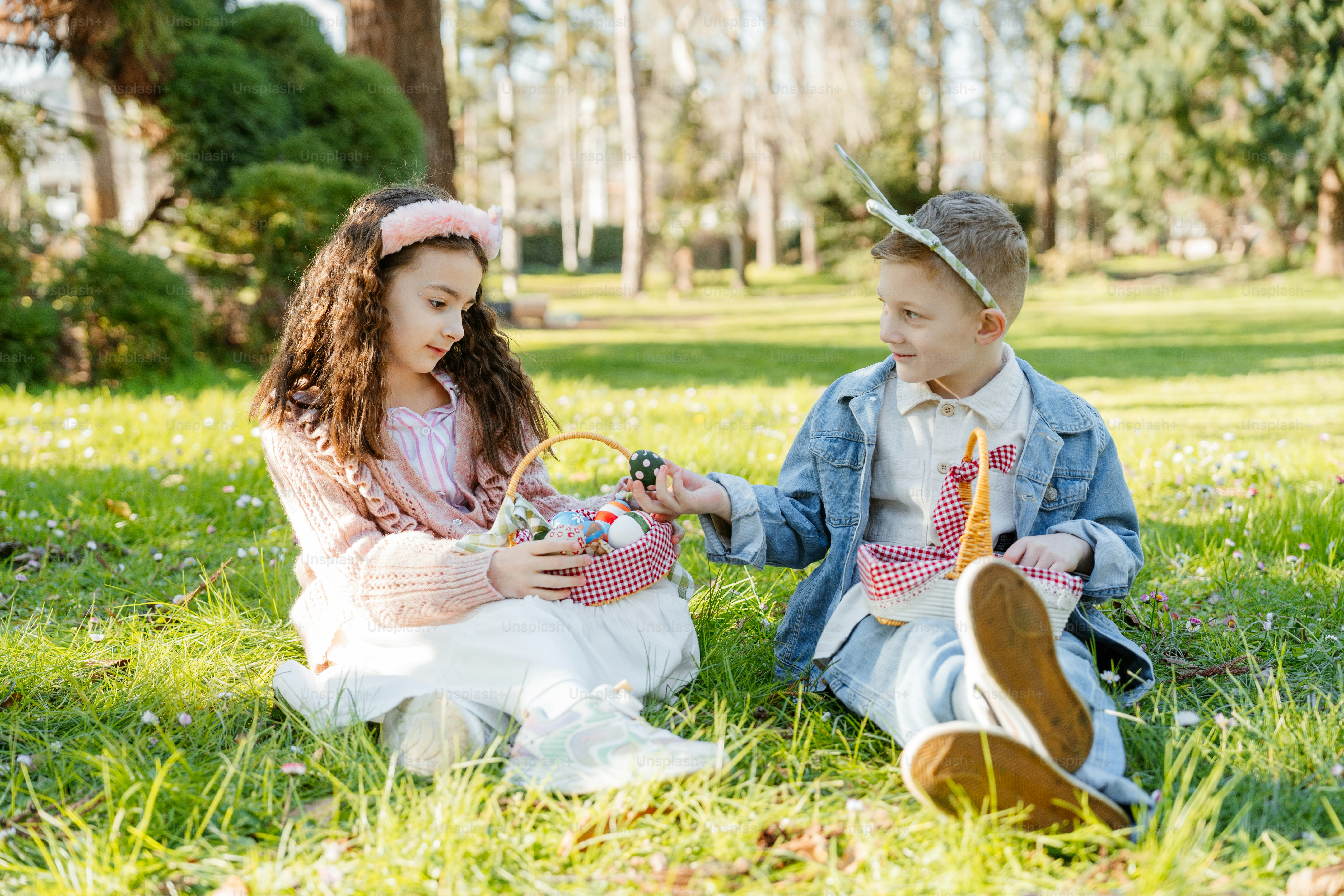잔디 위에 앉아 부활절 바구니를 든 두 아이