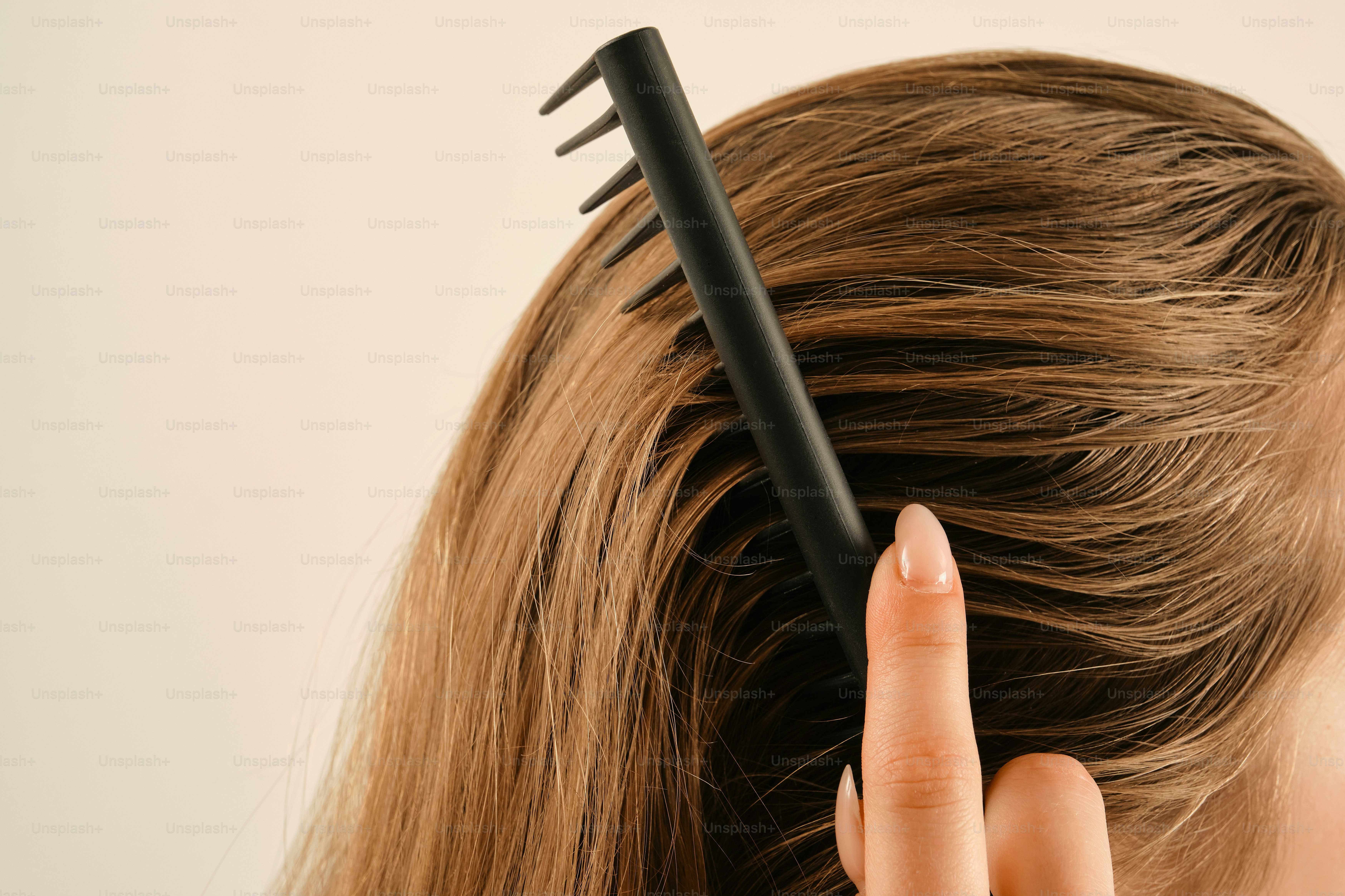 A hand combs long brown hair against a light background photo – Self ...