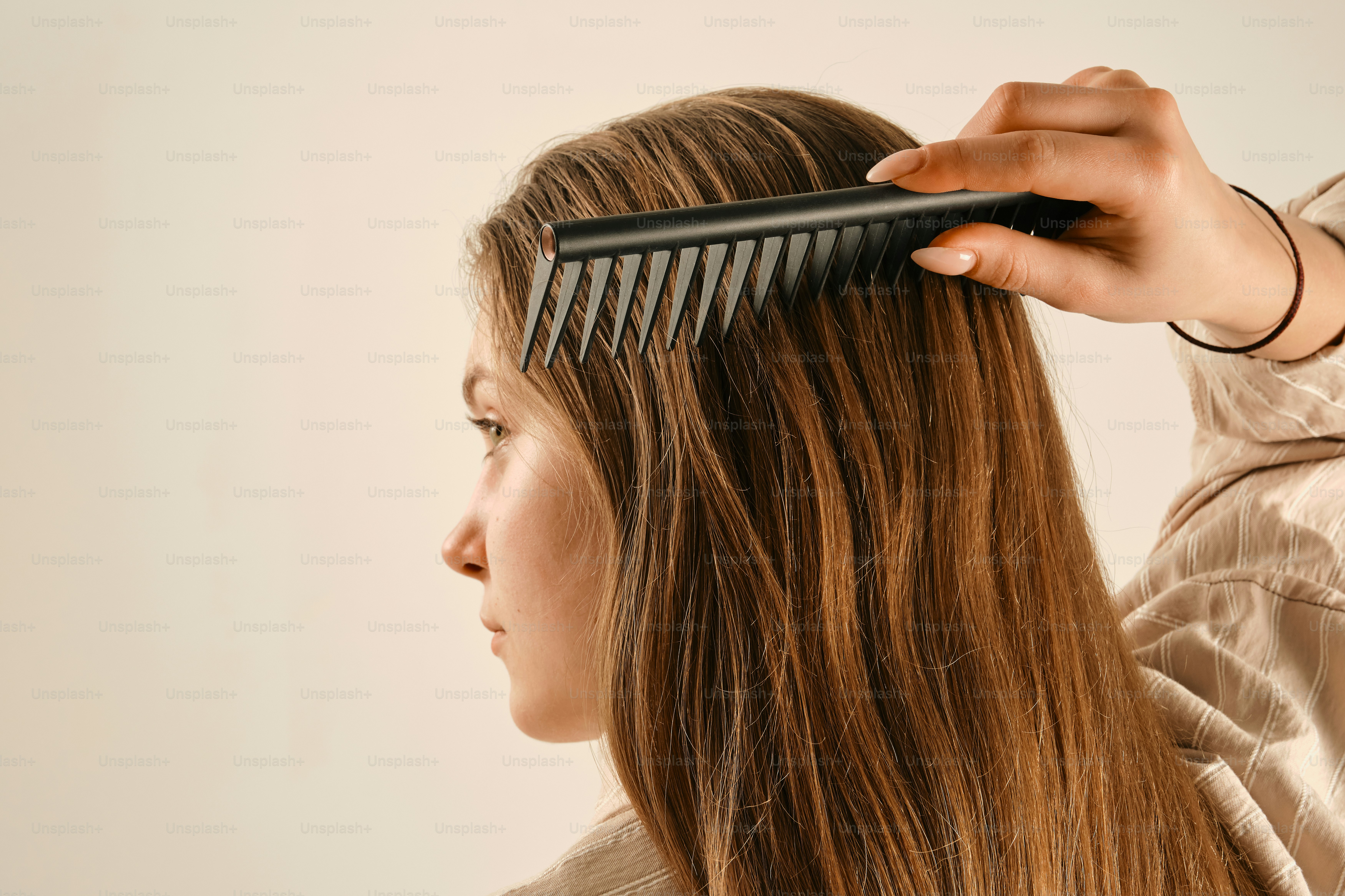 A hand combs long brown hair against a light background photo – Self ...