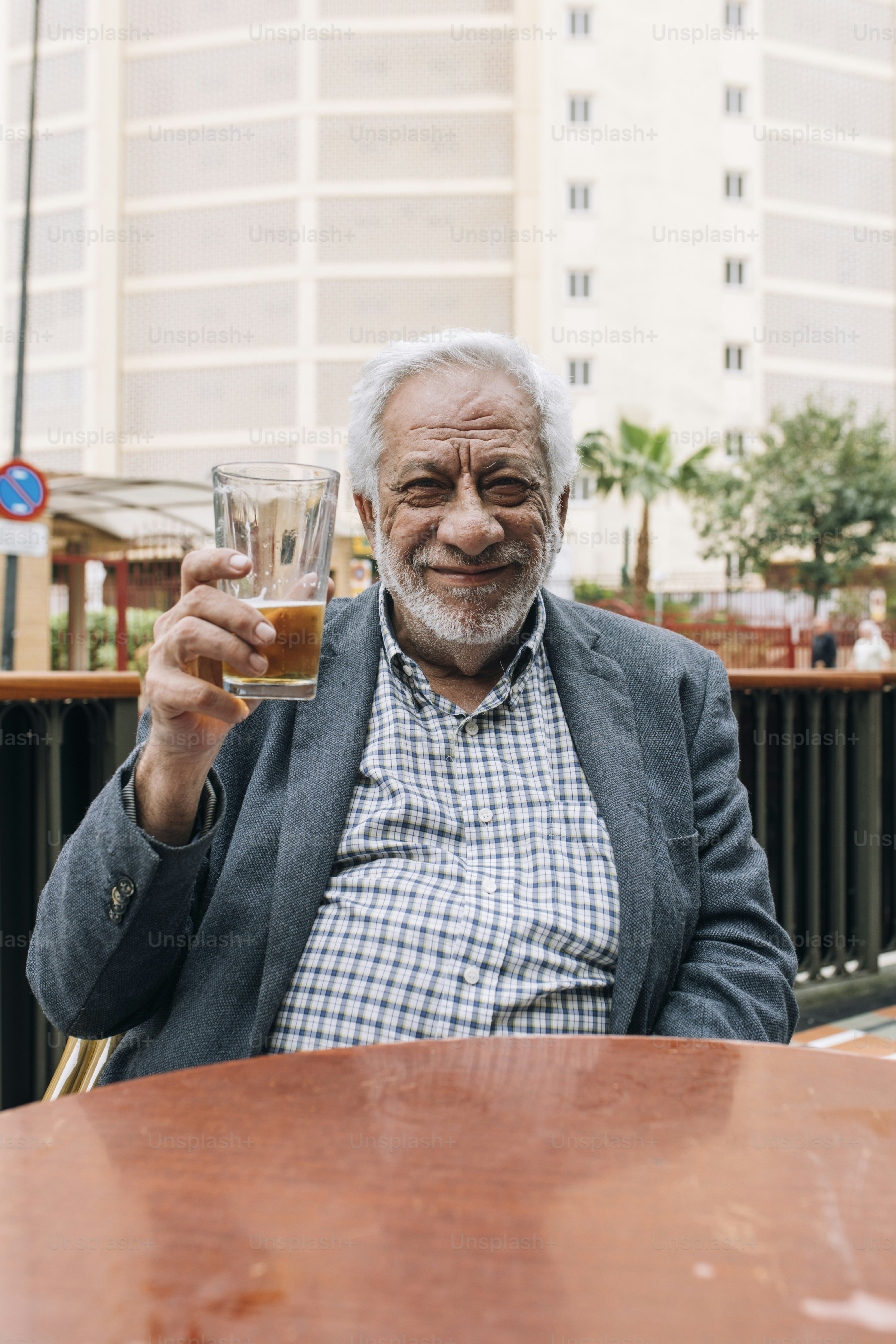 Homem idoso de cabelos brancos segurando um copo de bebida.