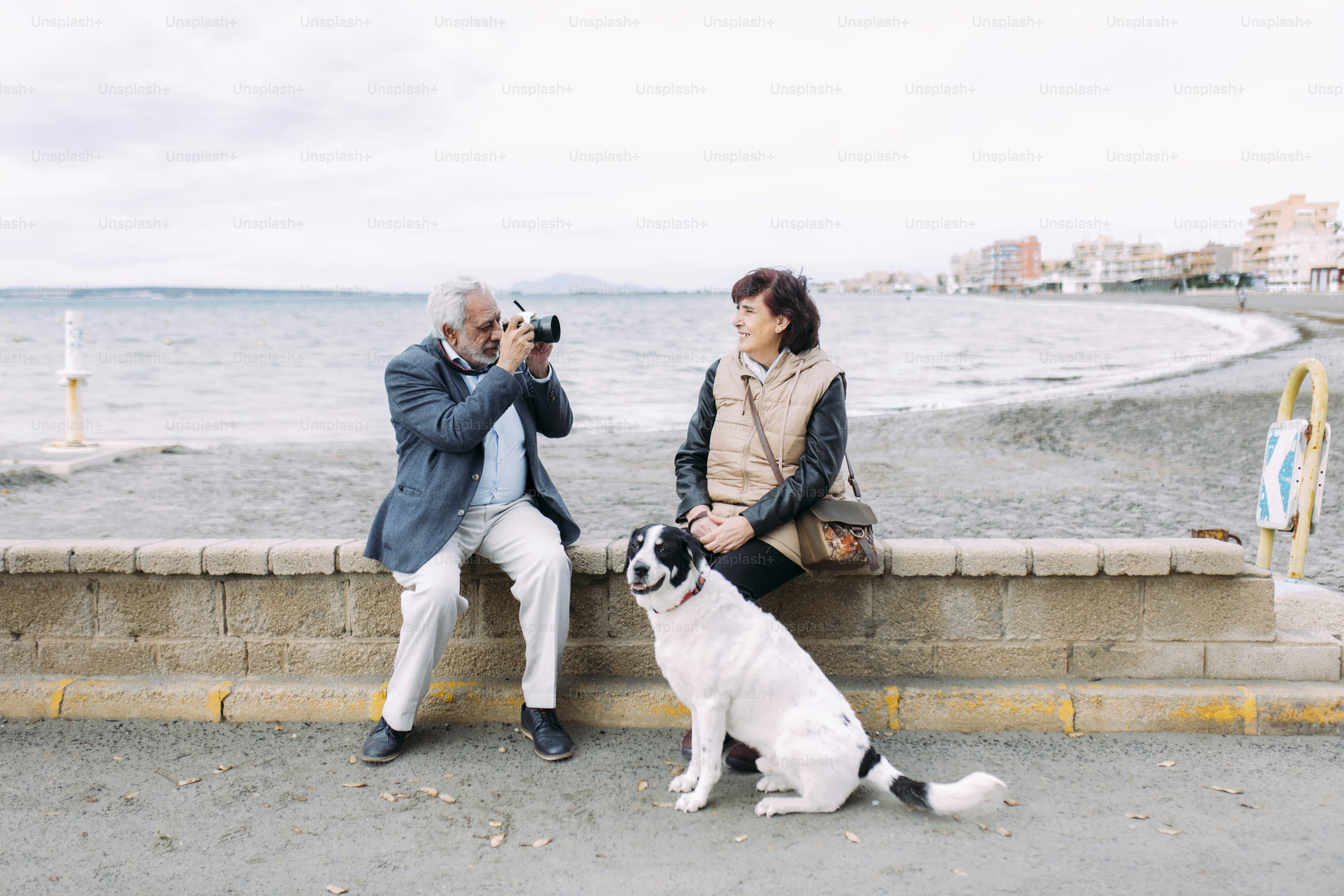 Homem tira foto de mulher e cachorro à beira do mar