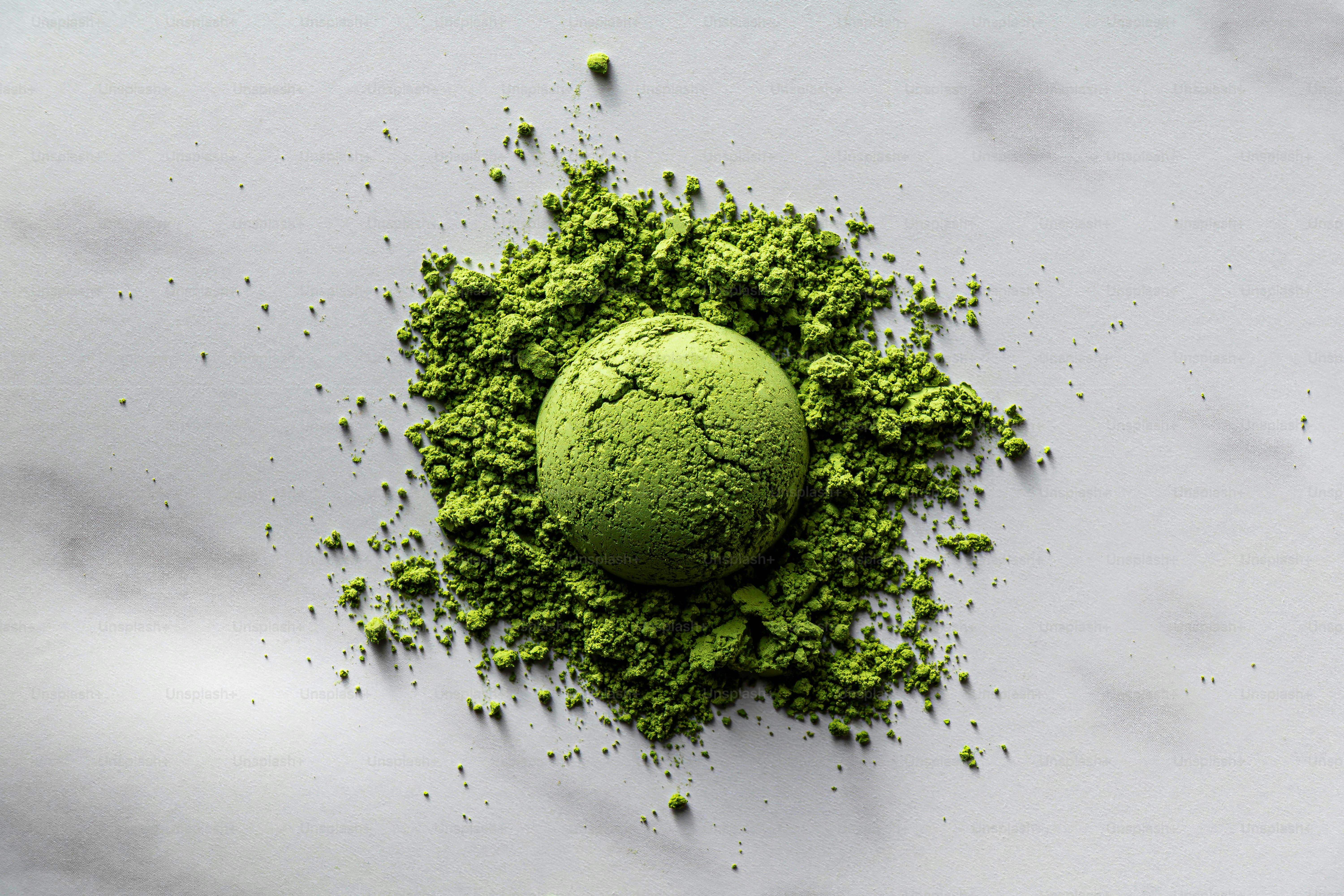 抹茶粉の山の上に一枚の緑のクッキーが乗っている。