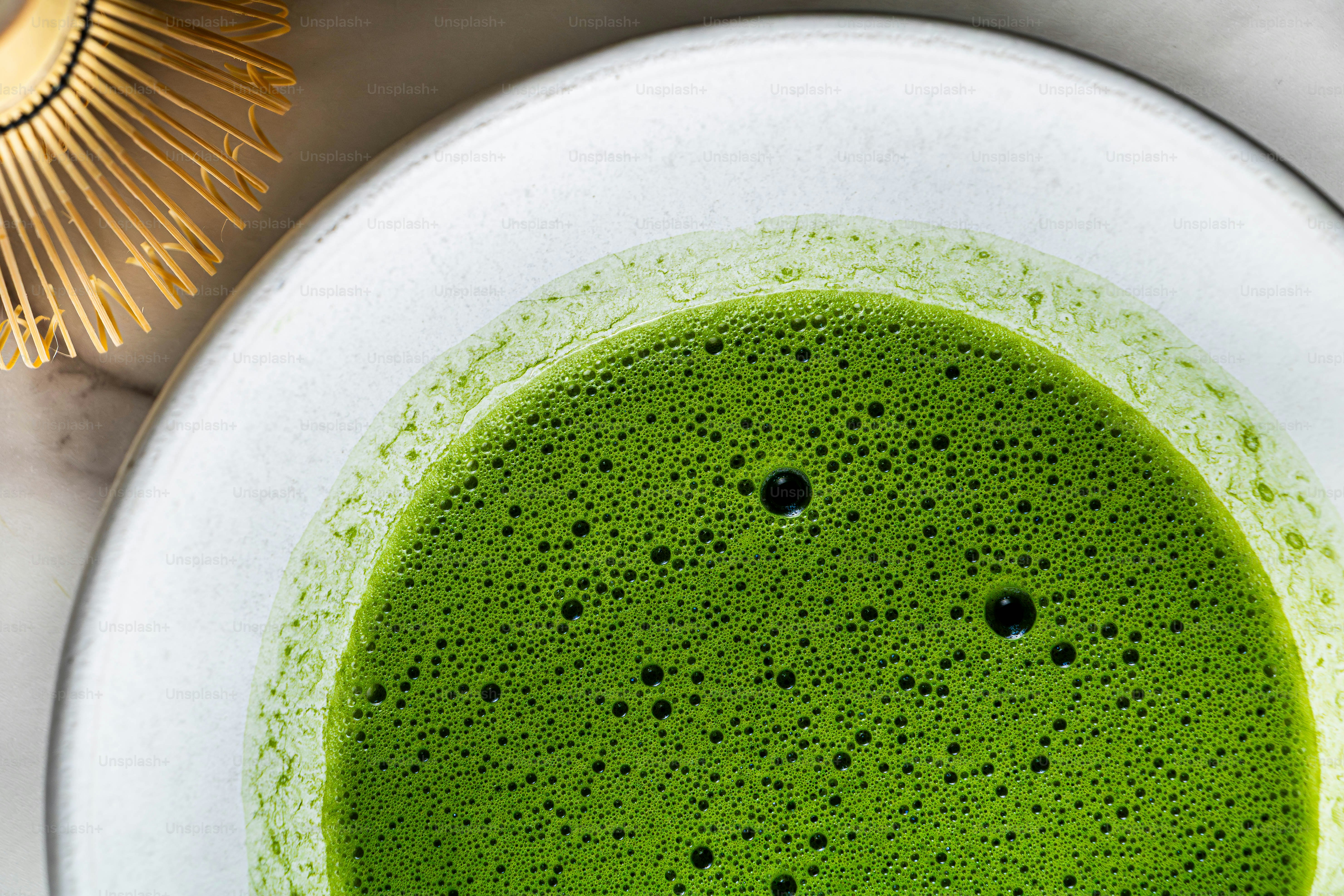 A frothy green matcha tea in a white bowl.