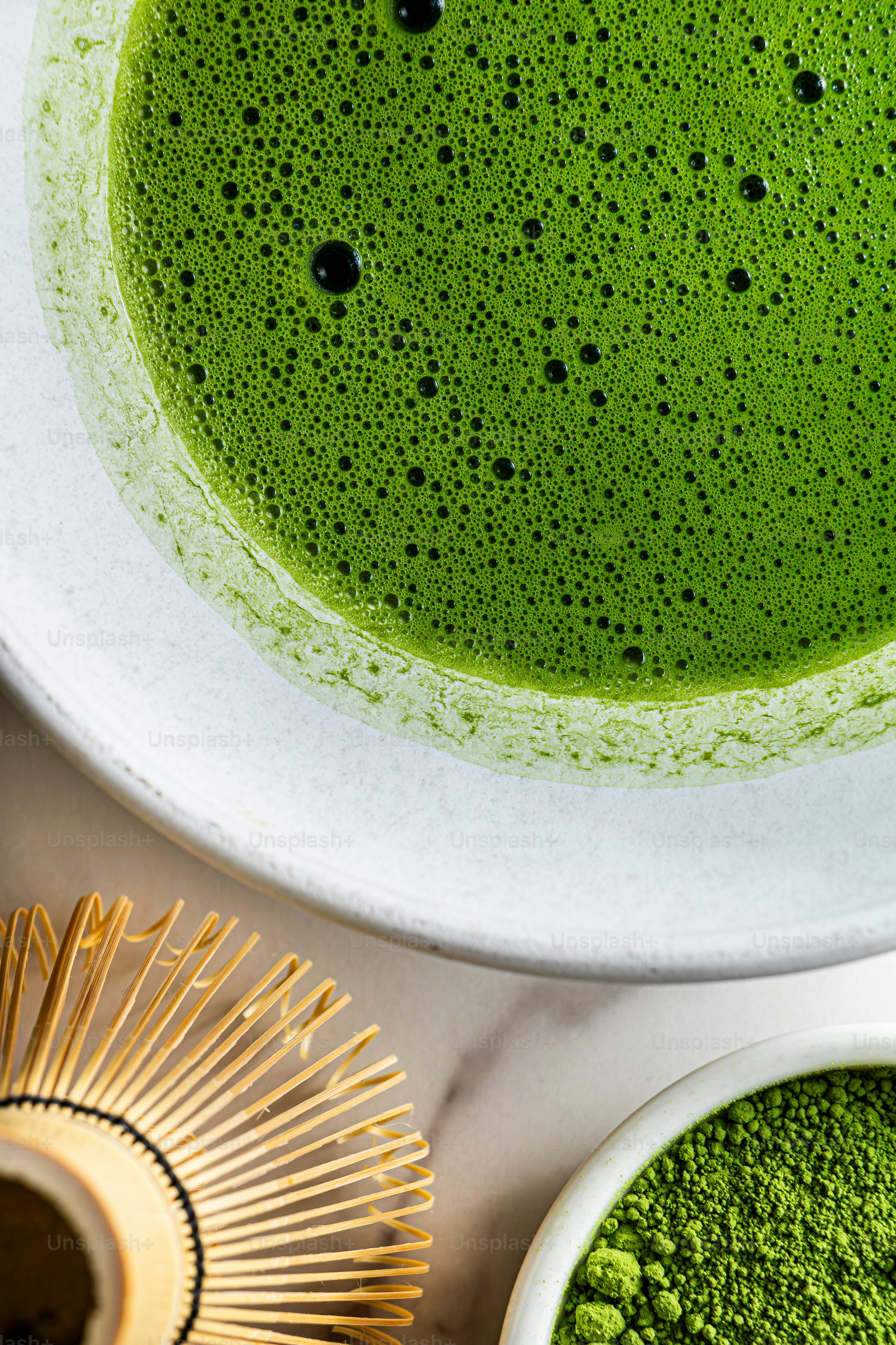 泡立つ緑色抹茶と竹製泡立て器