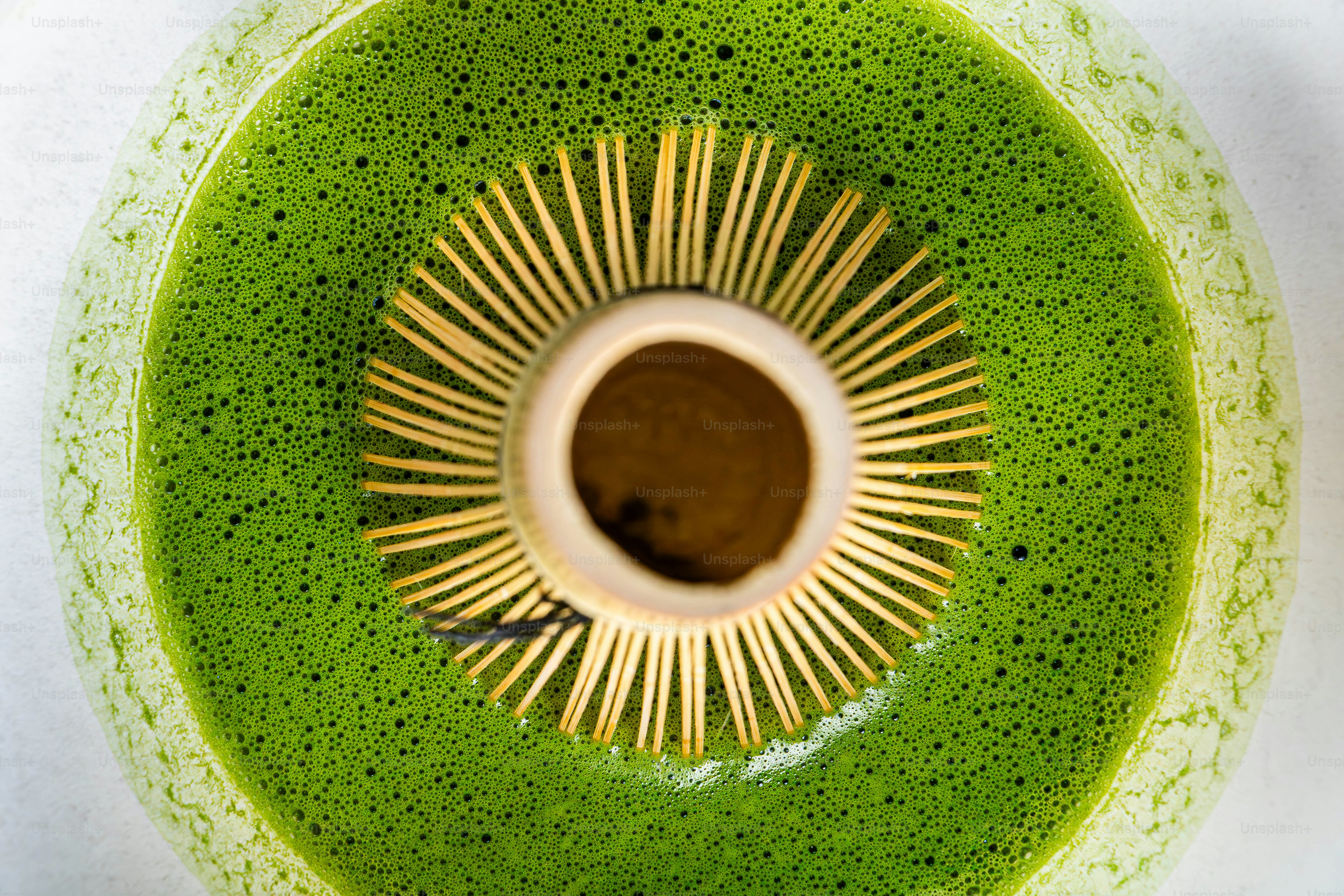 Close up of matcha tea being whisked in a bowl.