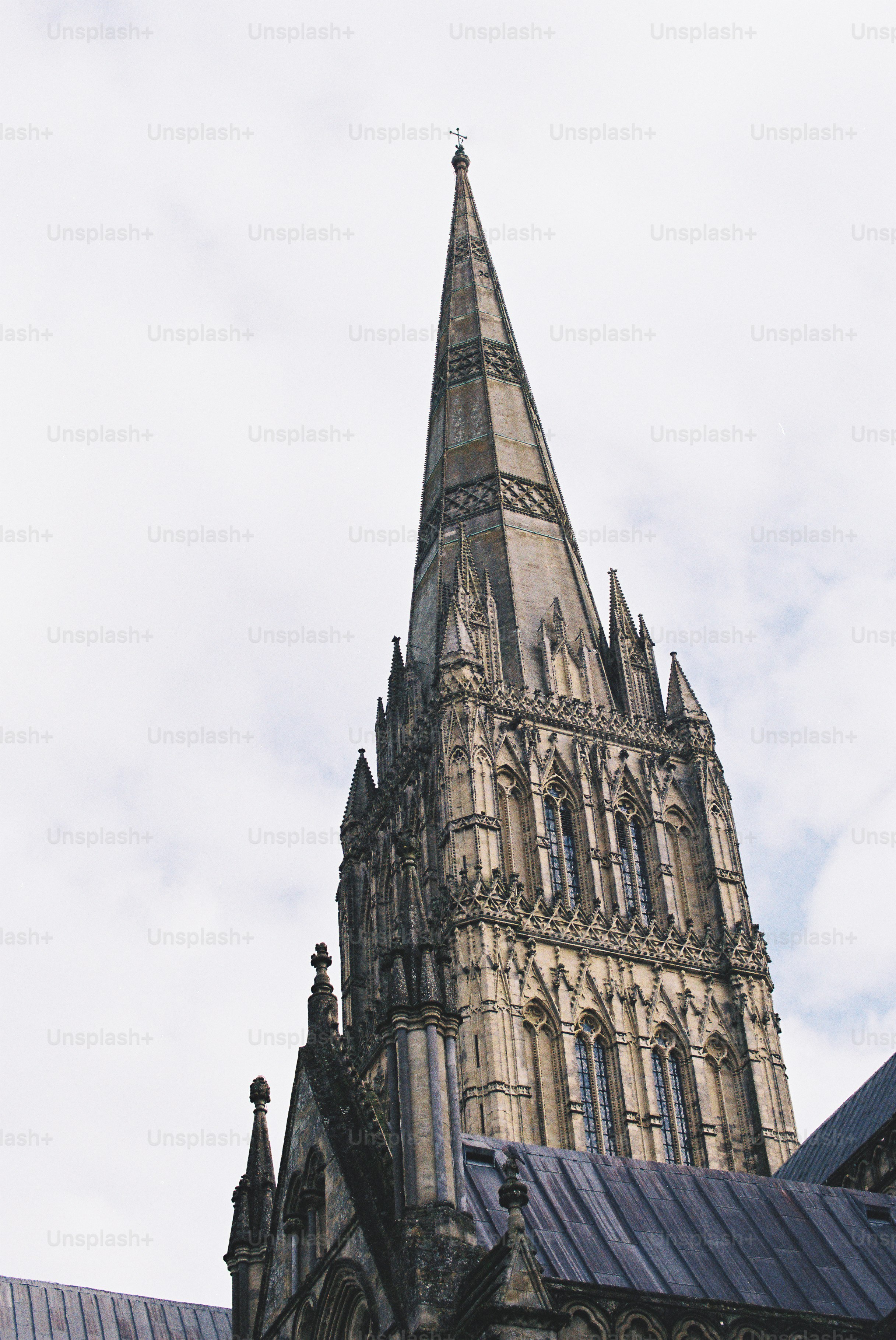 A tall gothic cathedral spire against a cloudy sky photo – Film Image ...