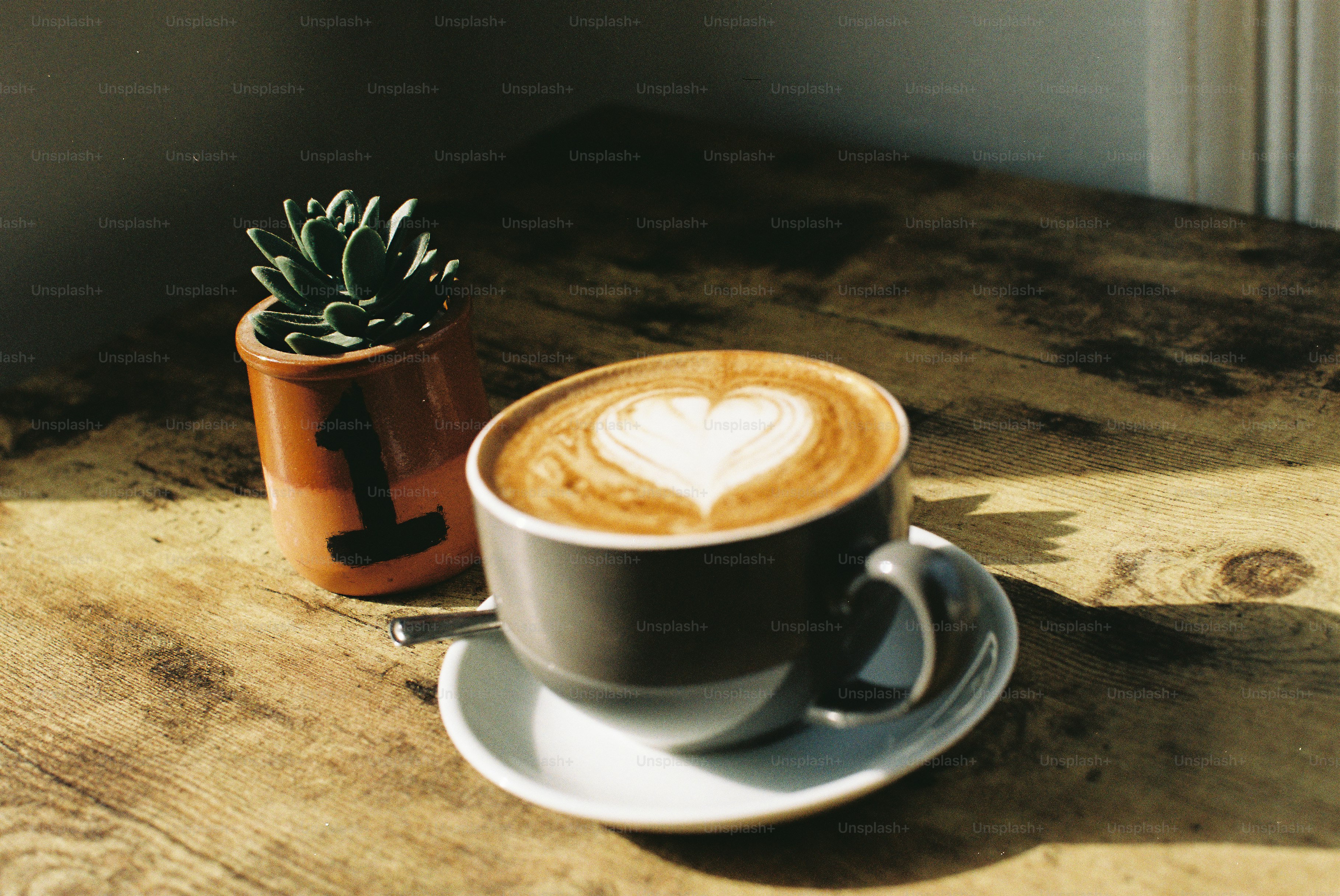 Latte art cuore in una tazza di caffè accanto alla pianta.