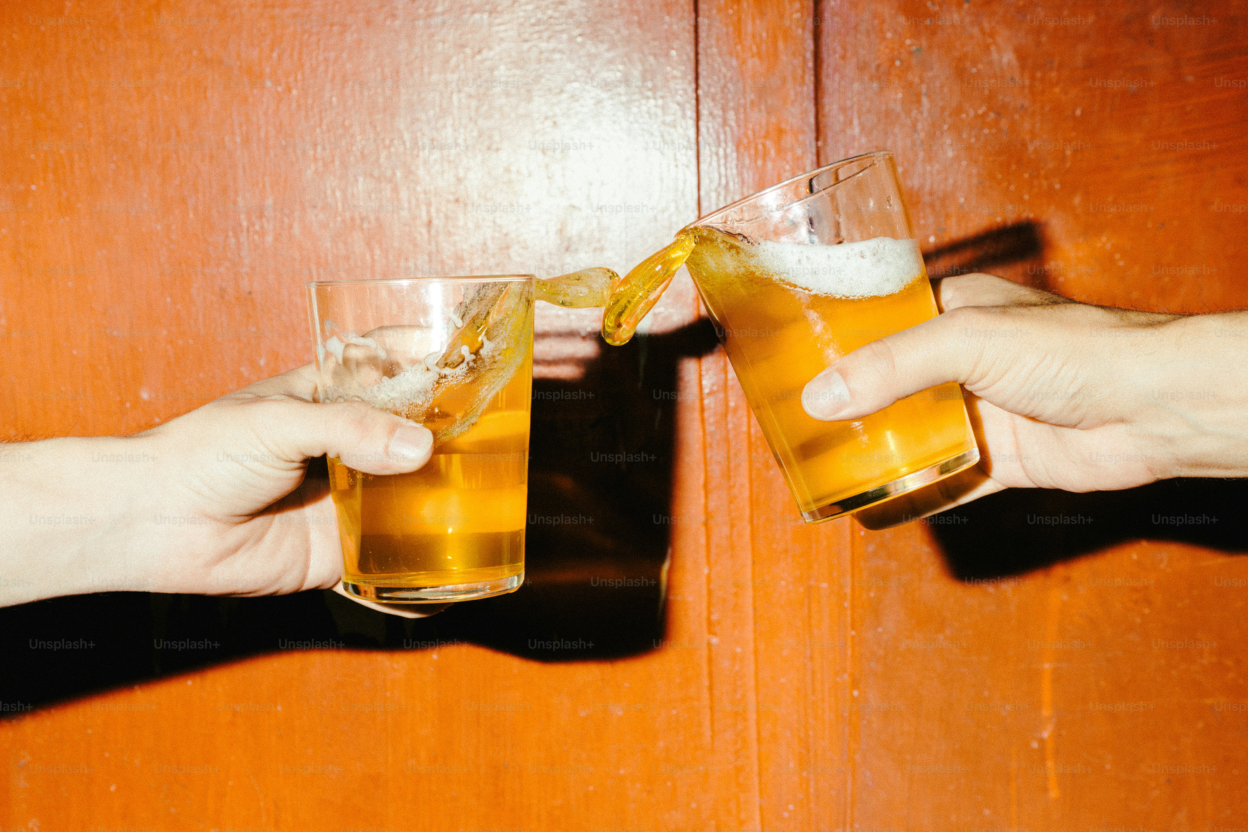 Two hands clinking glasses of amber liquid