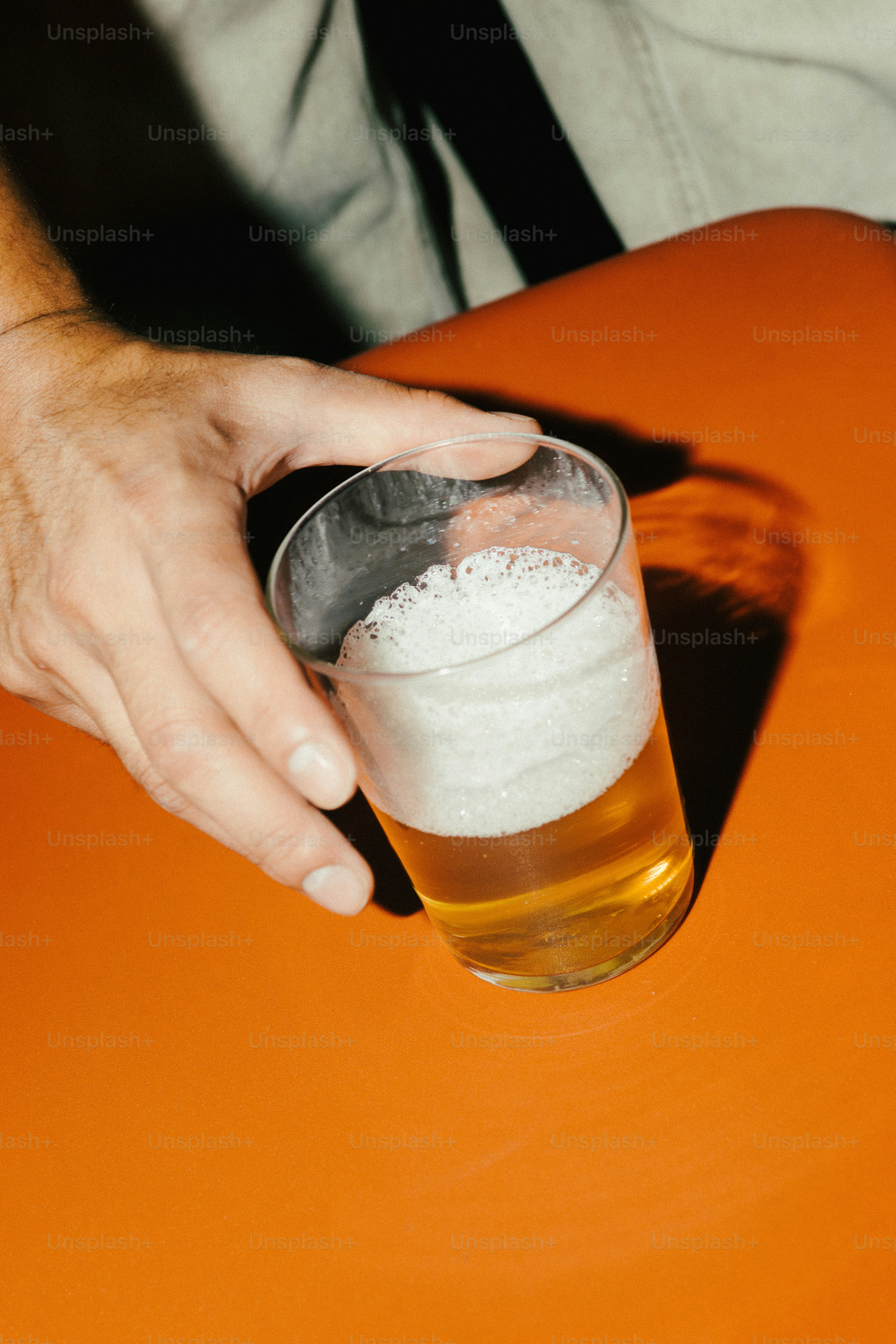 Una mano tiene un bicchiere di birra con schiuma.