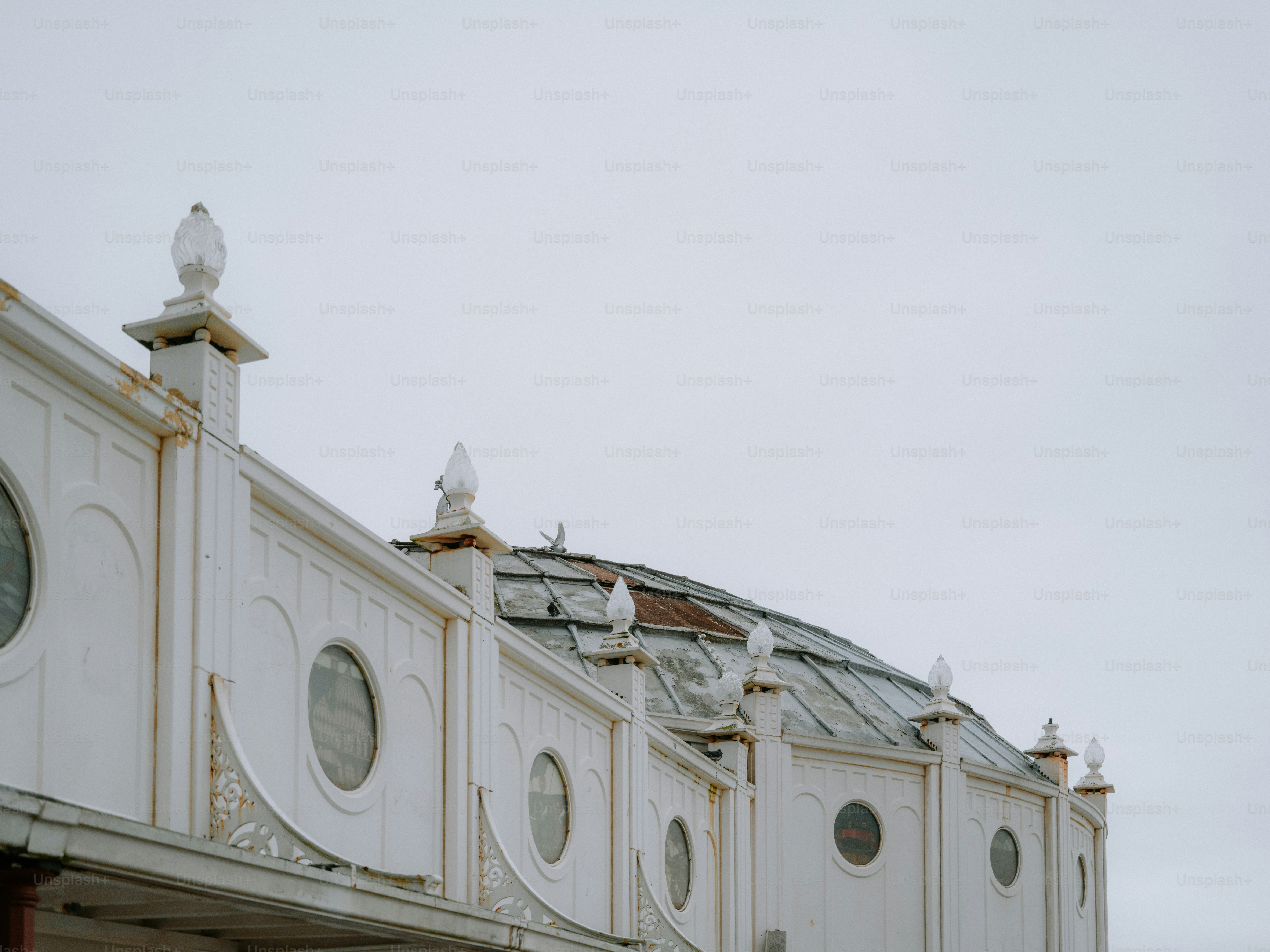 Edificio blanco ornamentado con ventanas redondas bajo un cielo gris