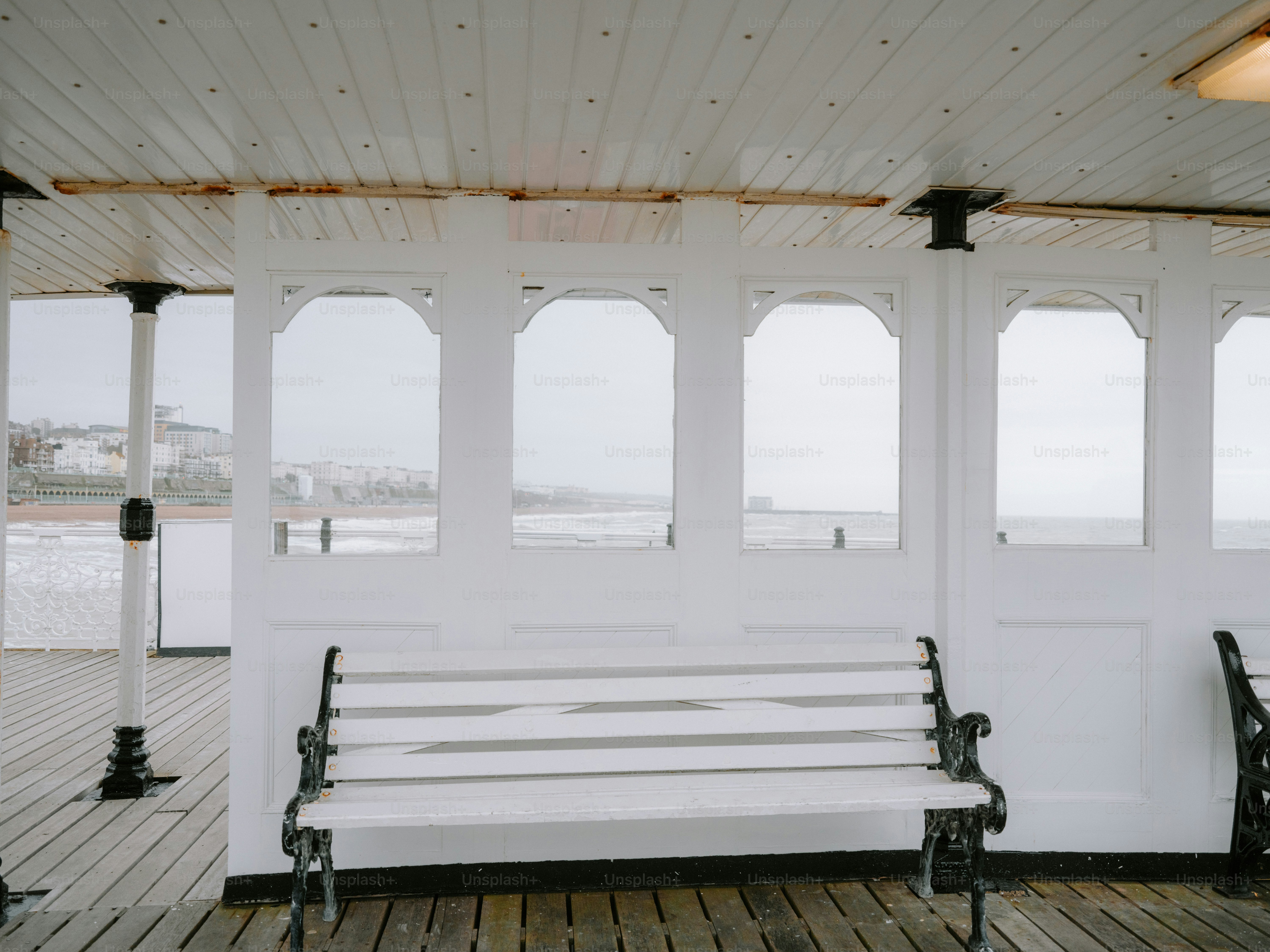 Bancos blancos en un muelle de madera con vistas al océano