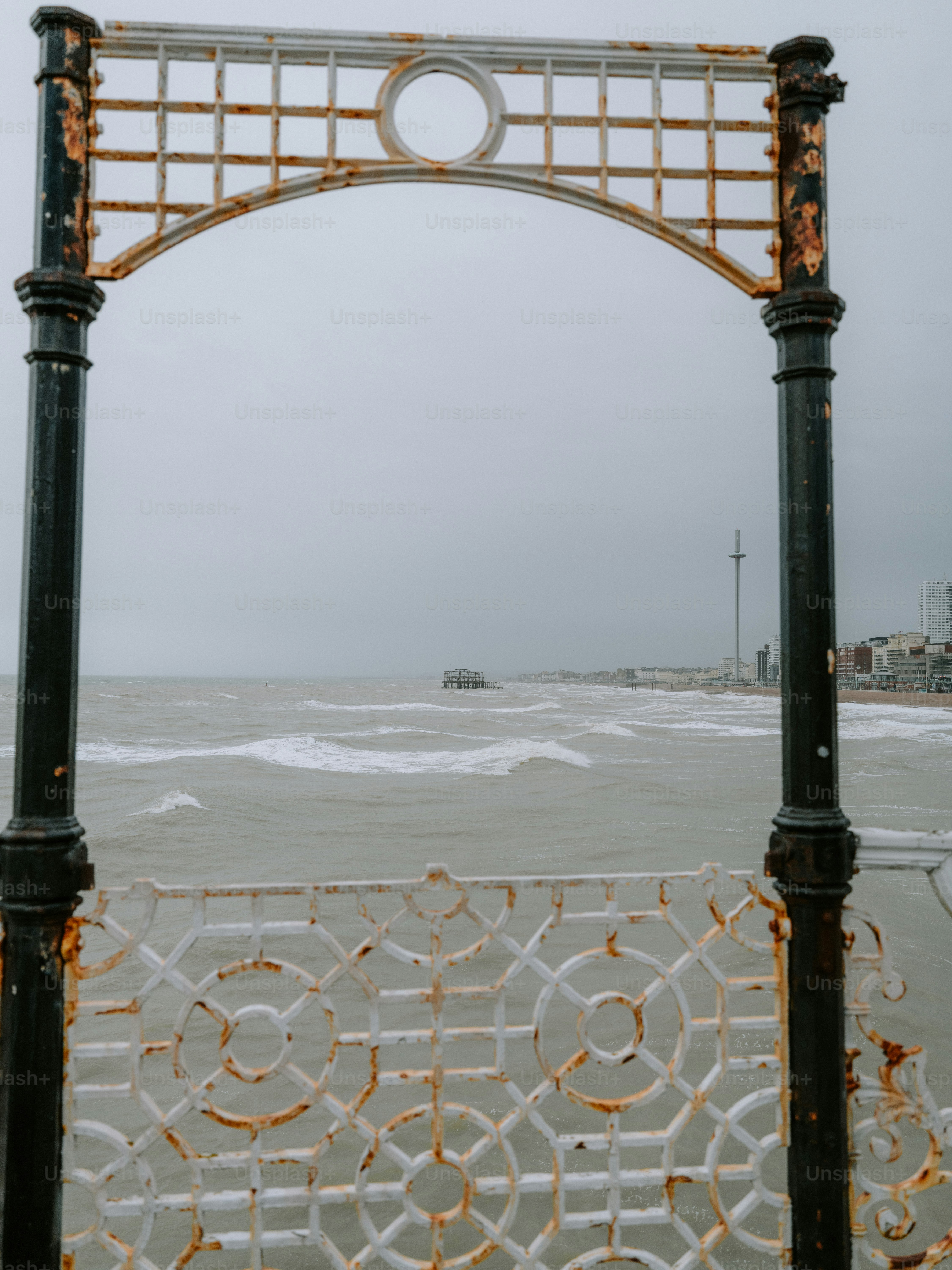 Mar tormentoso visto a través de un arco oxidado de muelle.