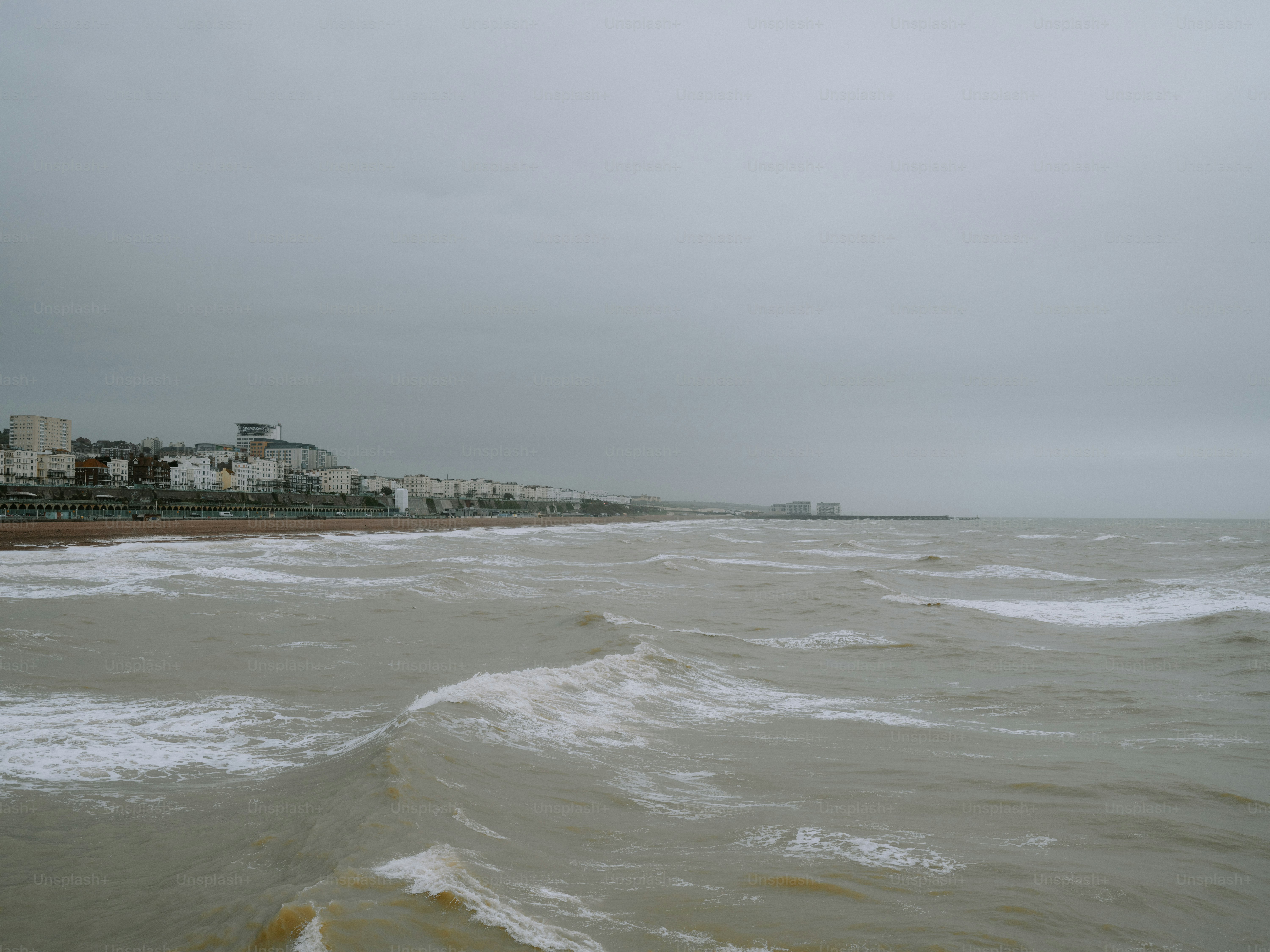 海辺の町の近くで、曇り空の下、荒れた波が