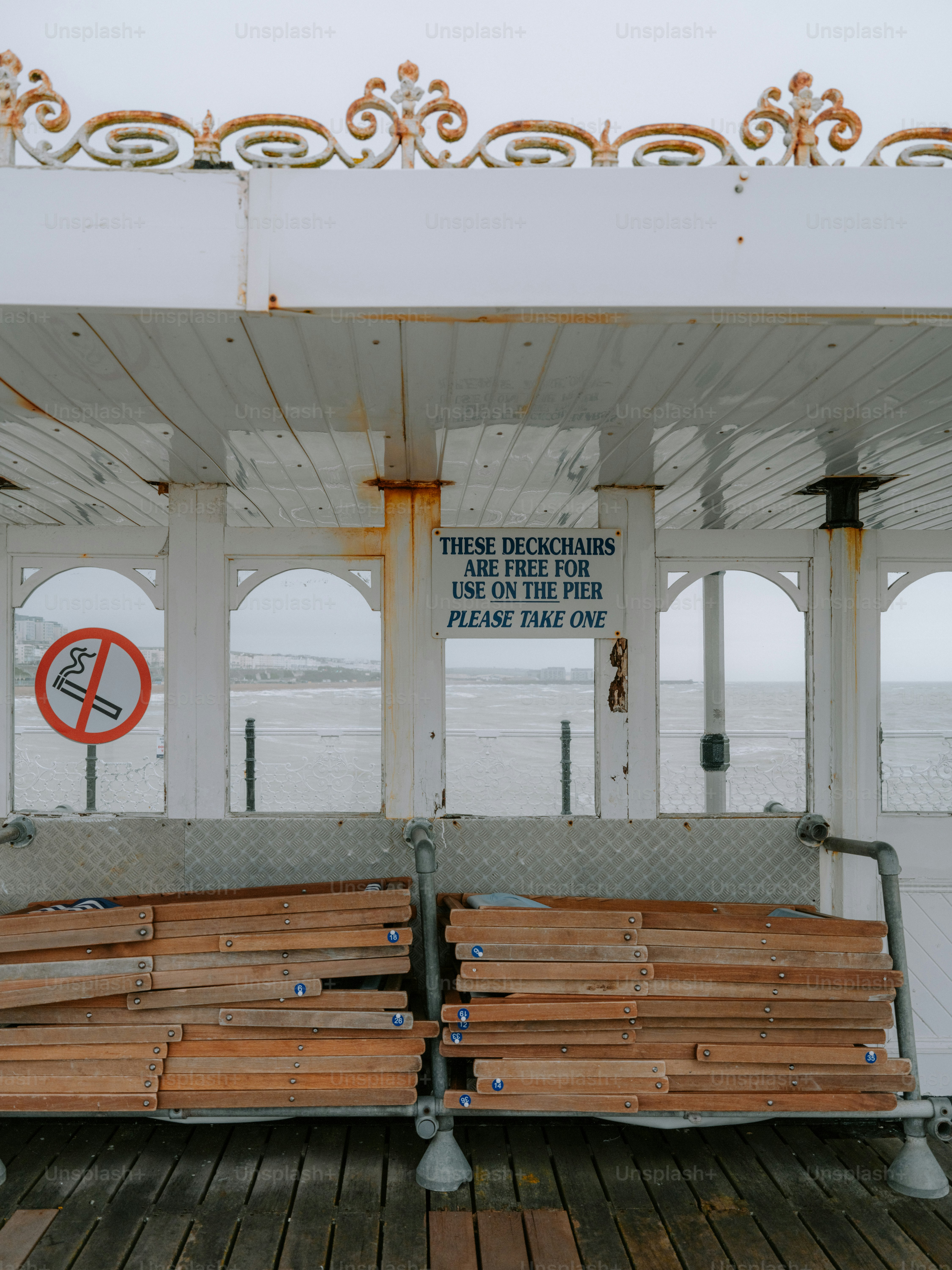 Sdraio vuote su un molo con un cartello di divieto di fumare.
