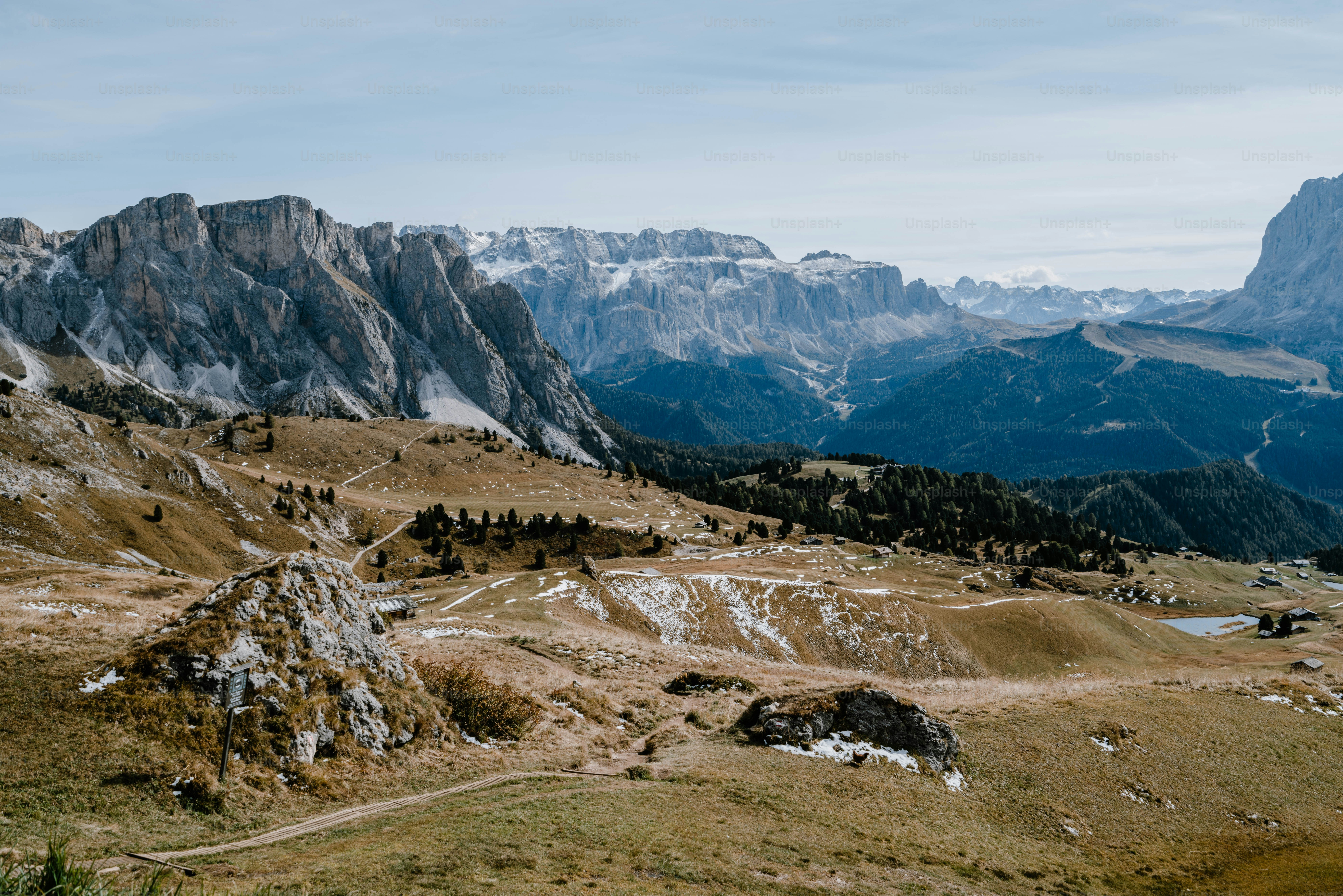 Rugged mountain landscape with dry grass and distant snow peaks. photo ...
