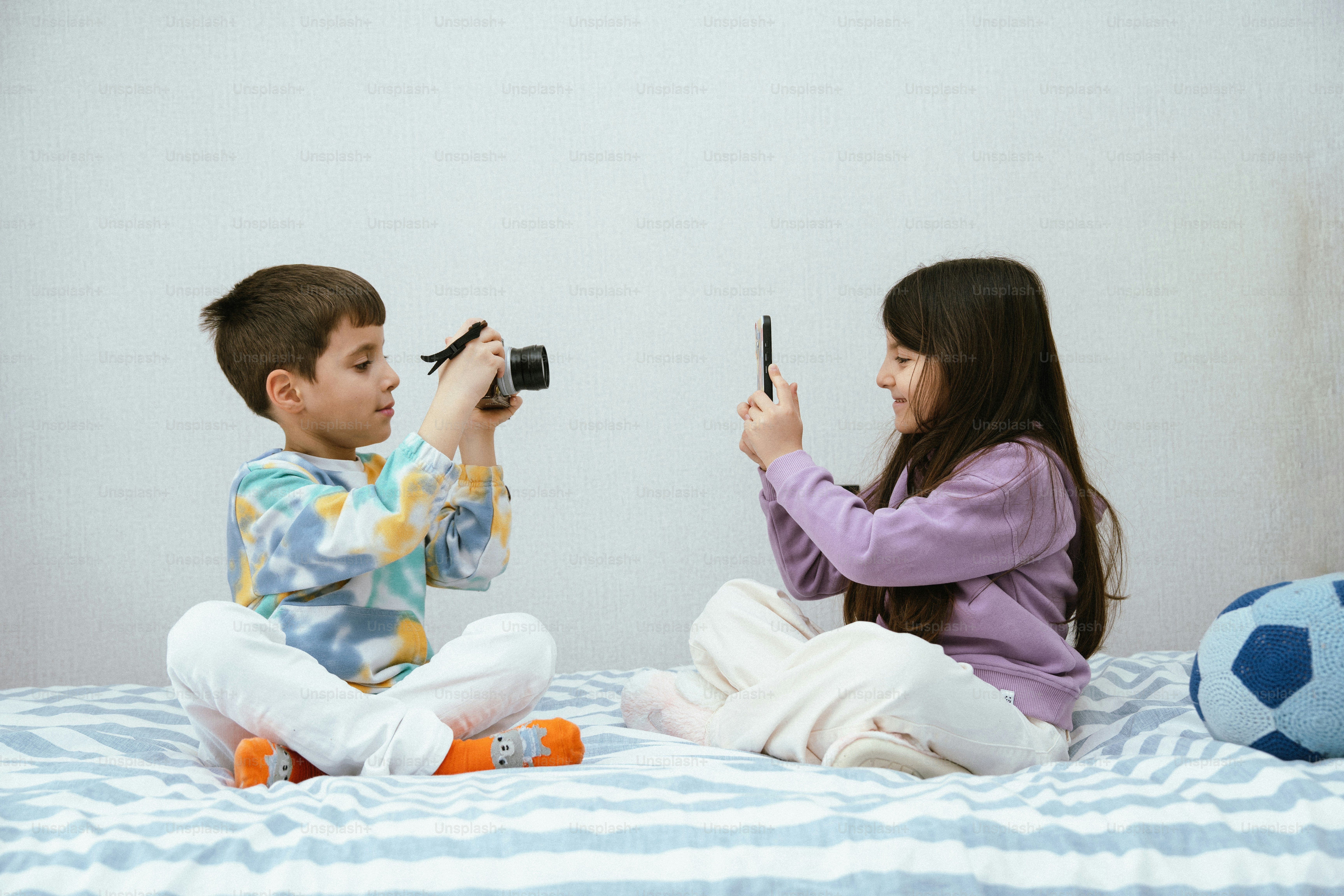 Dos niños haciendo fotos con cámara y móvil.