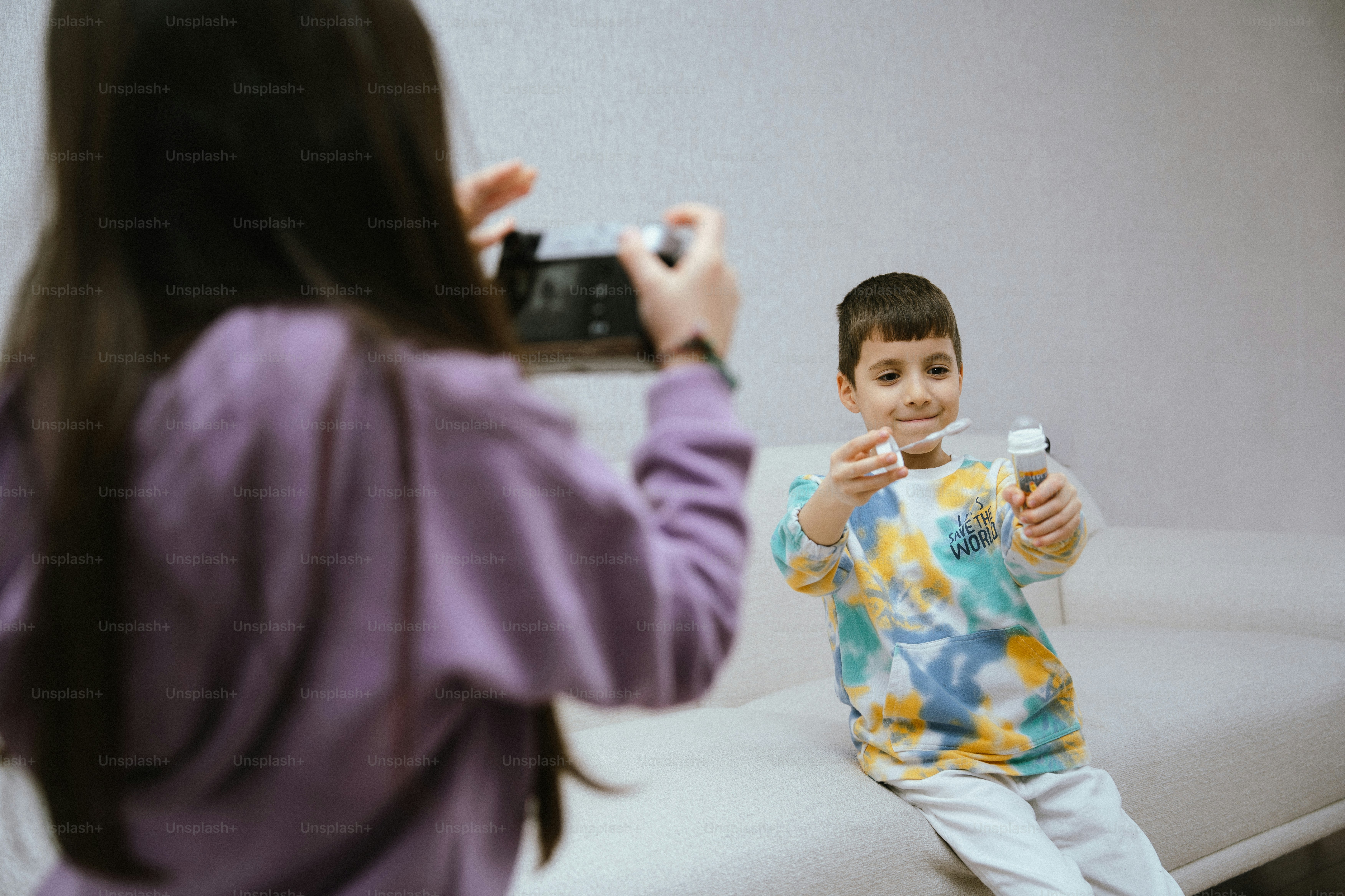 Chica haciendo una foto a un chico sosteniendo objetos
