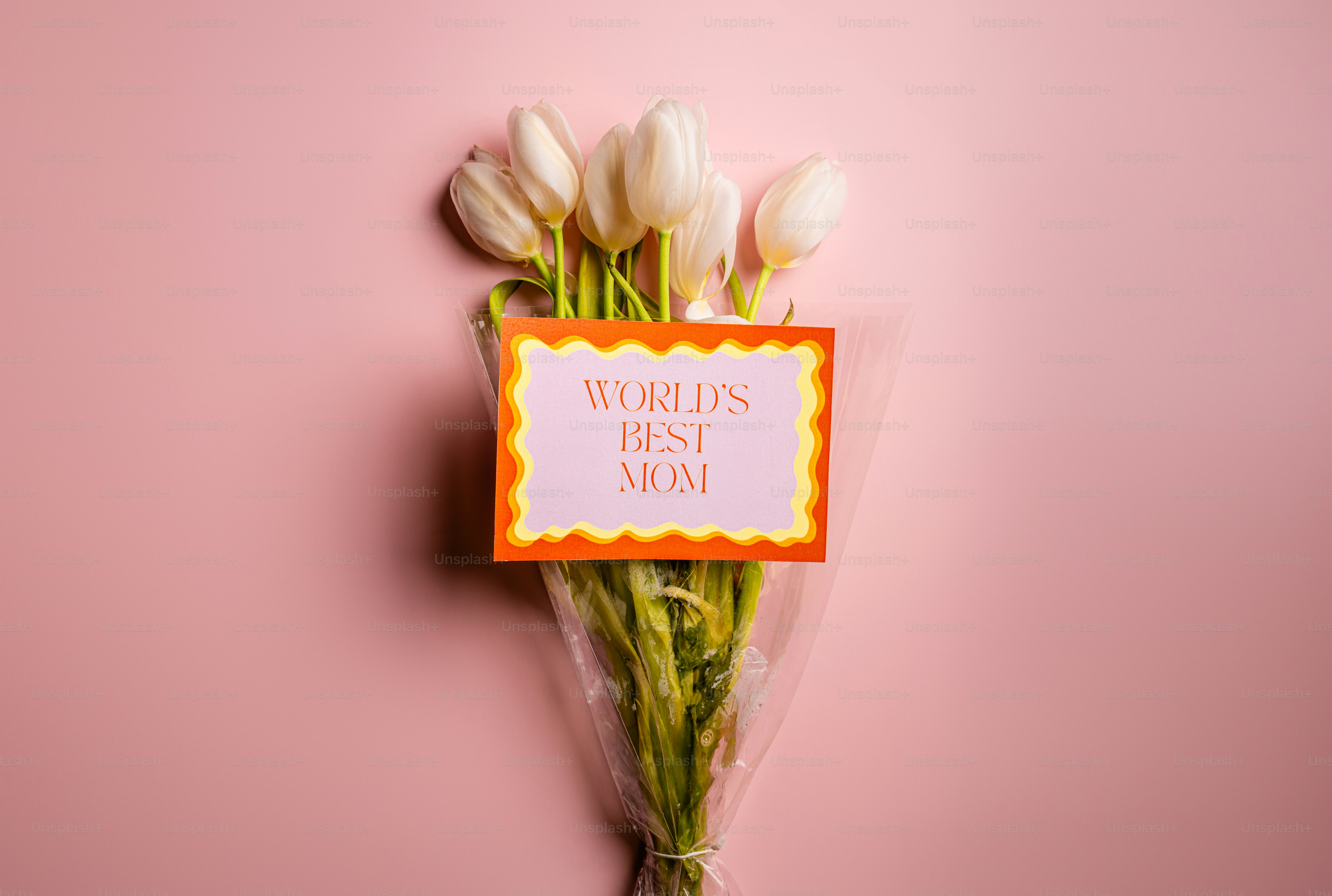 Tulipanes blancos con la tarjeta de "la mejor madre del mundo" sobre fondo rosa