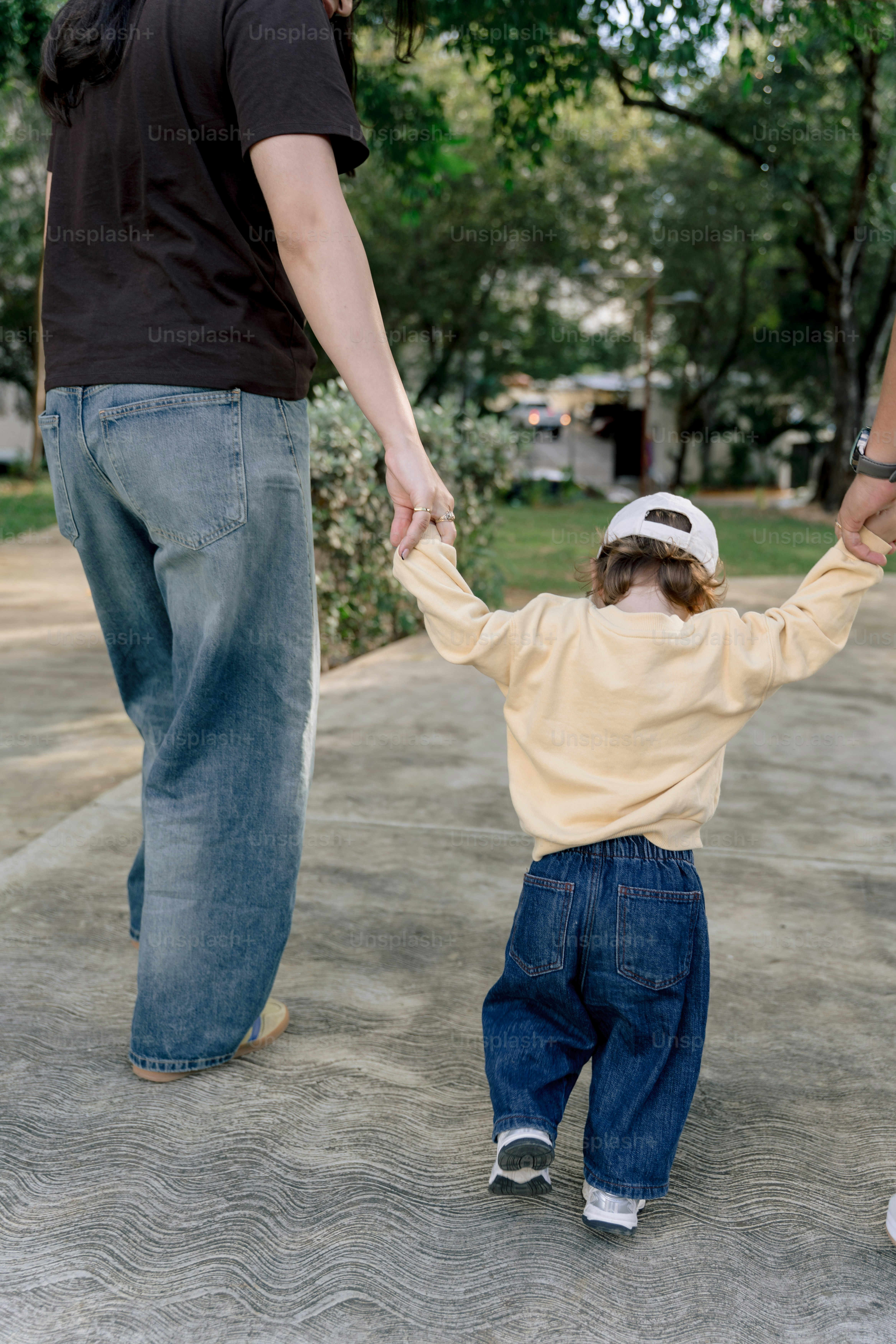 Adulto segurando as mãos de uma criança caminhando no caminho