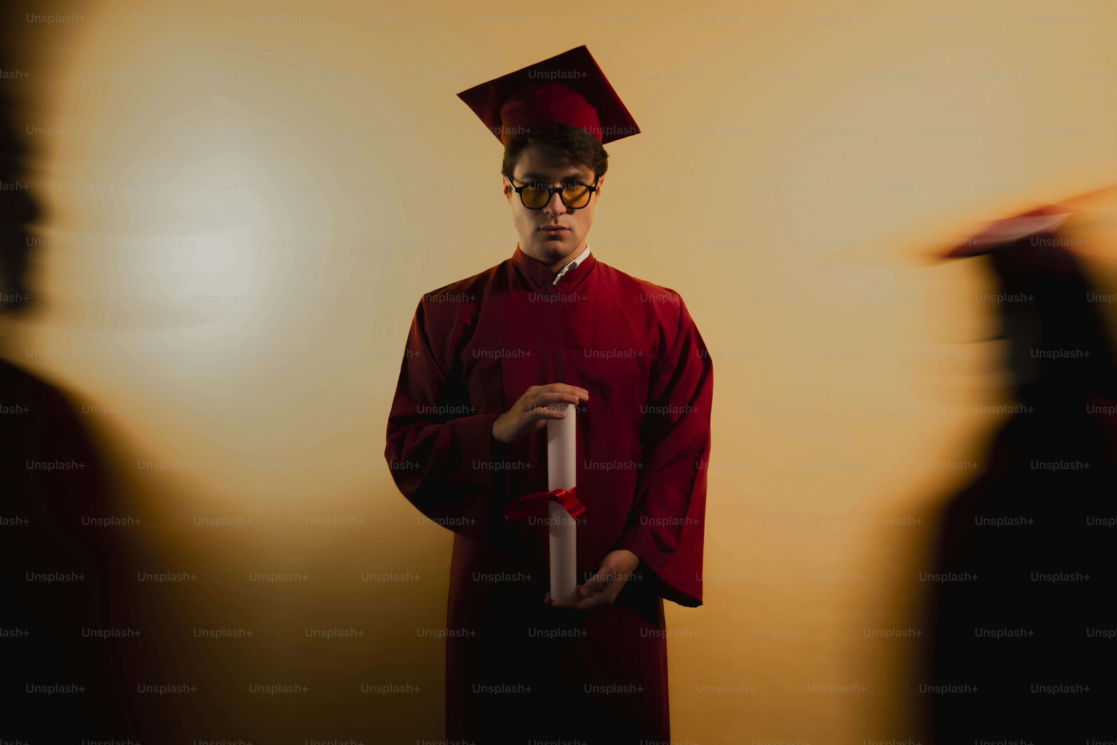 Graduate in cap and gown holds diploma with blurred figures photo   Education Image on Unsplash