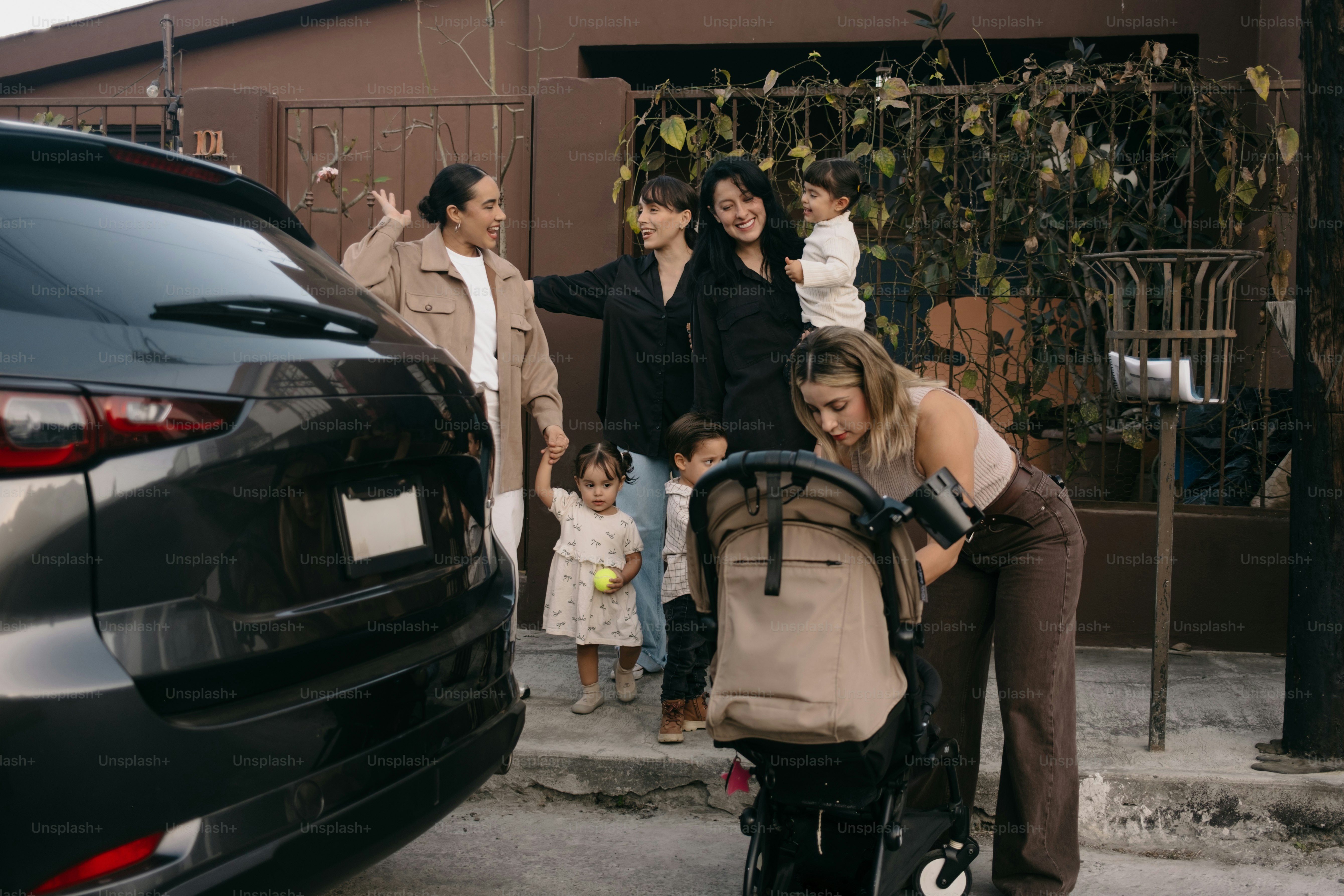 La famille se rassemble autour d’une poussette près d’une voiture garée.