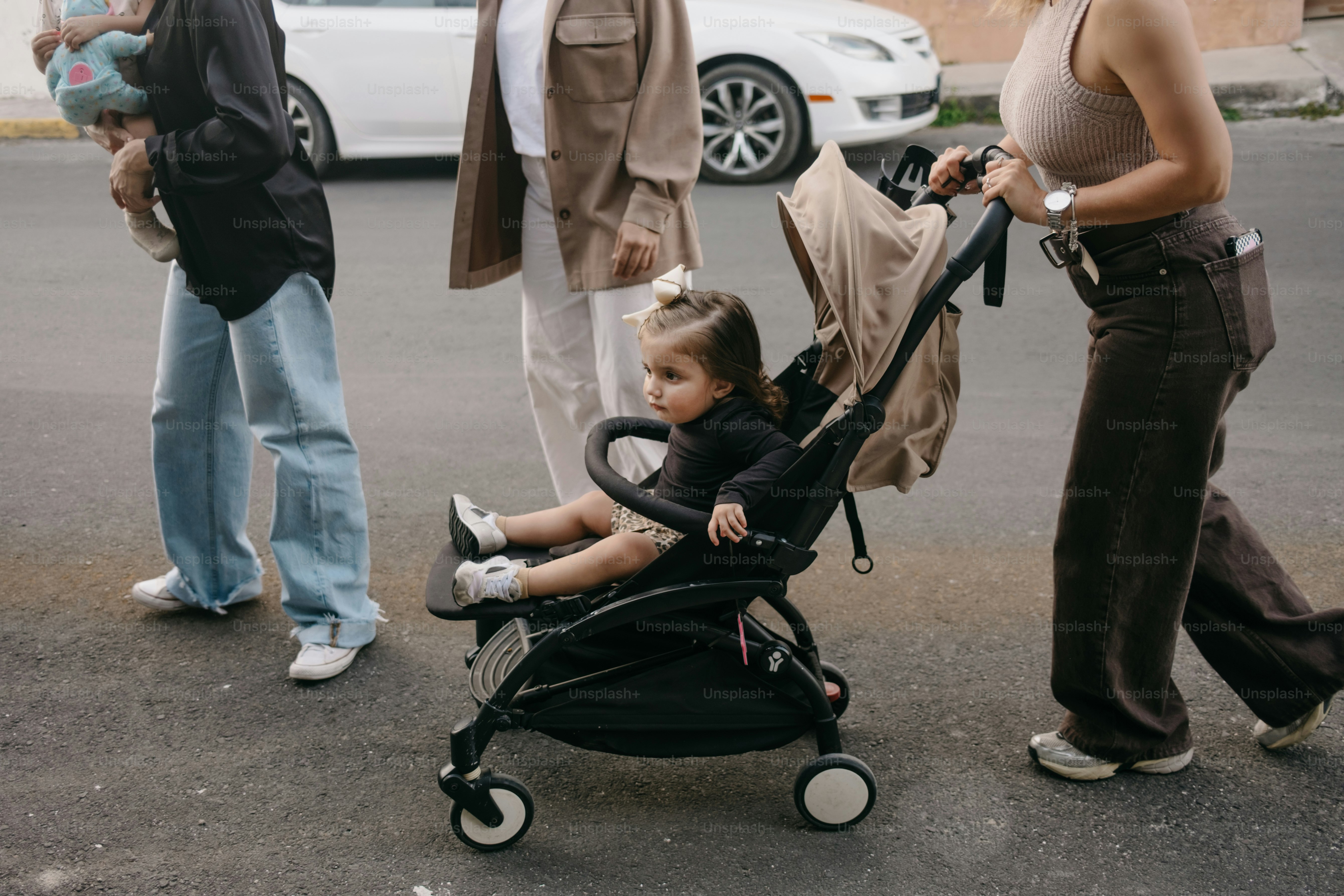 Un bébé est assis dans une poussette pendant que les gens marchent