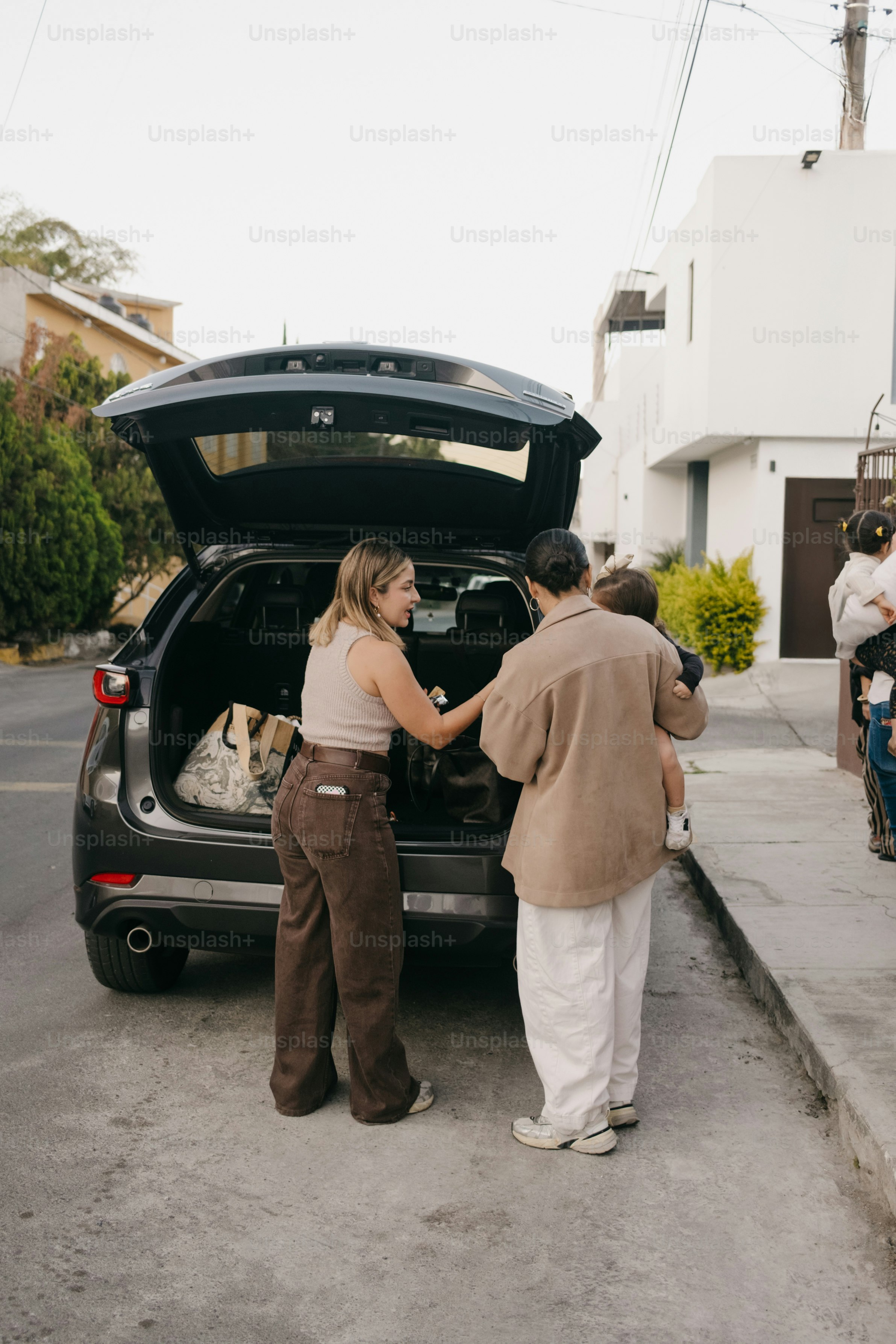 Des gens chargeant des bagages dans un coffre de voiture