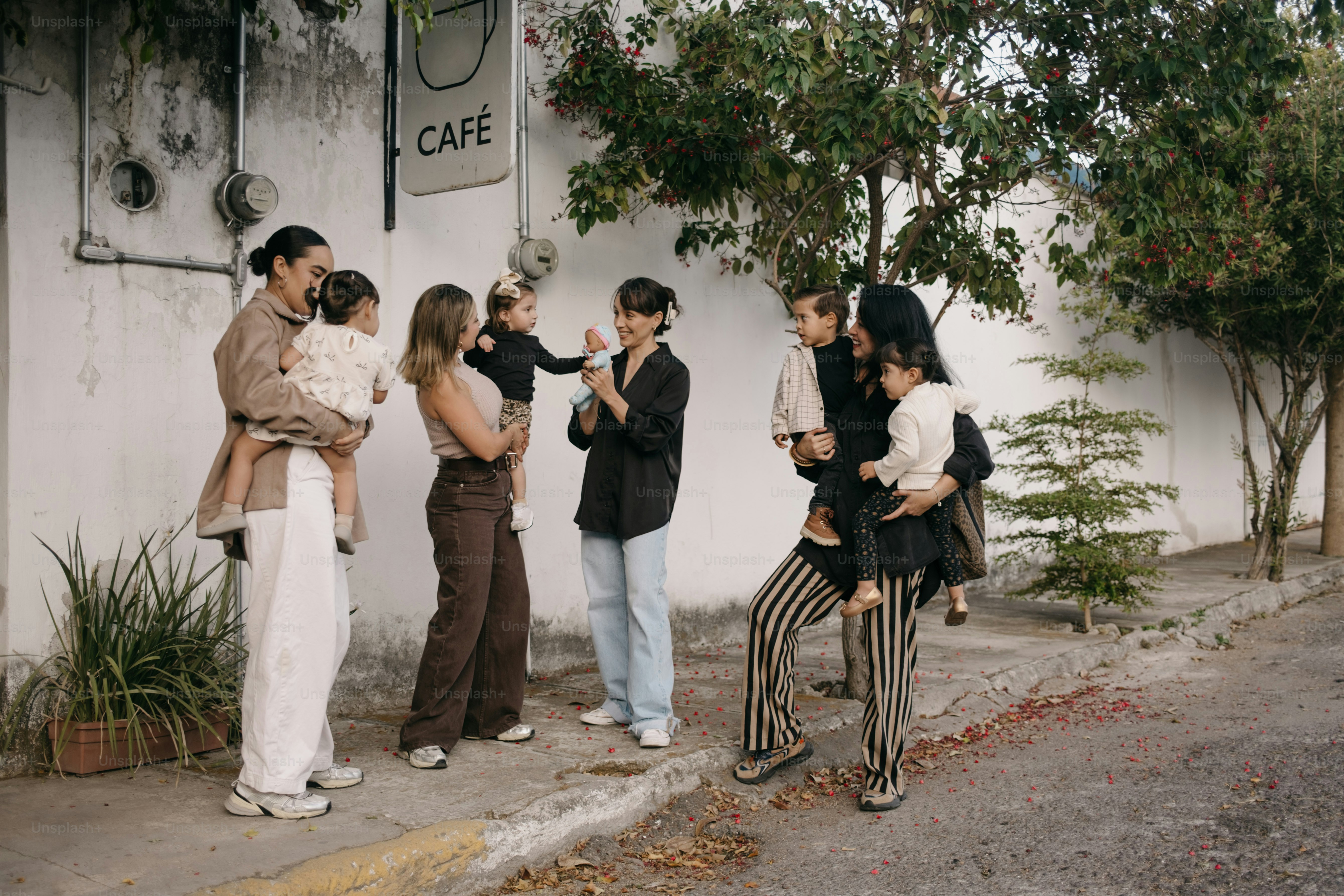 Plusieurs adultes et enfants se rassemblent près d’une enseigne de café.