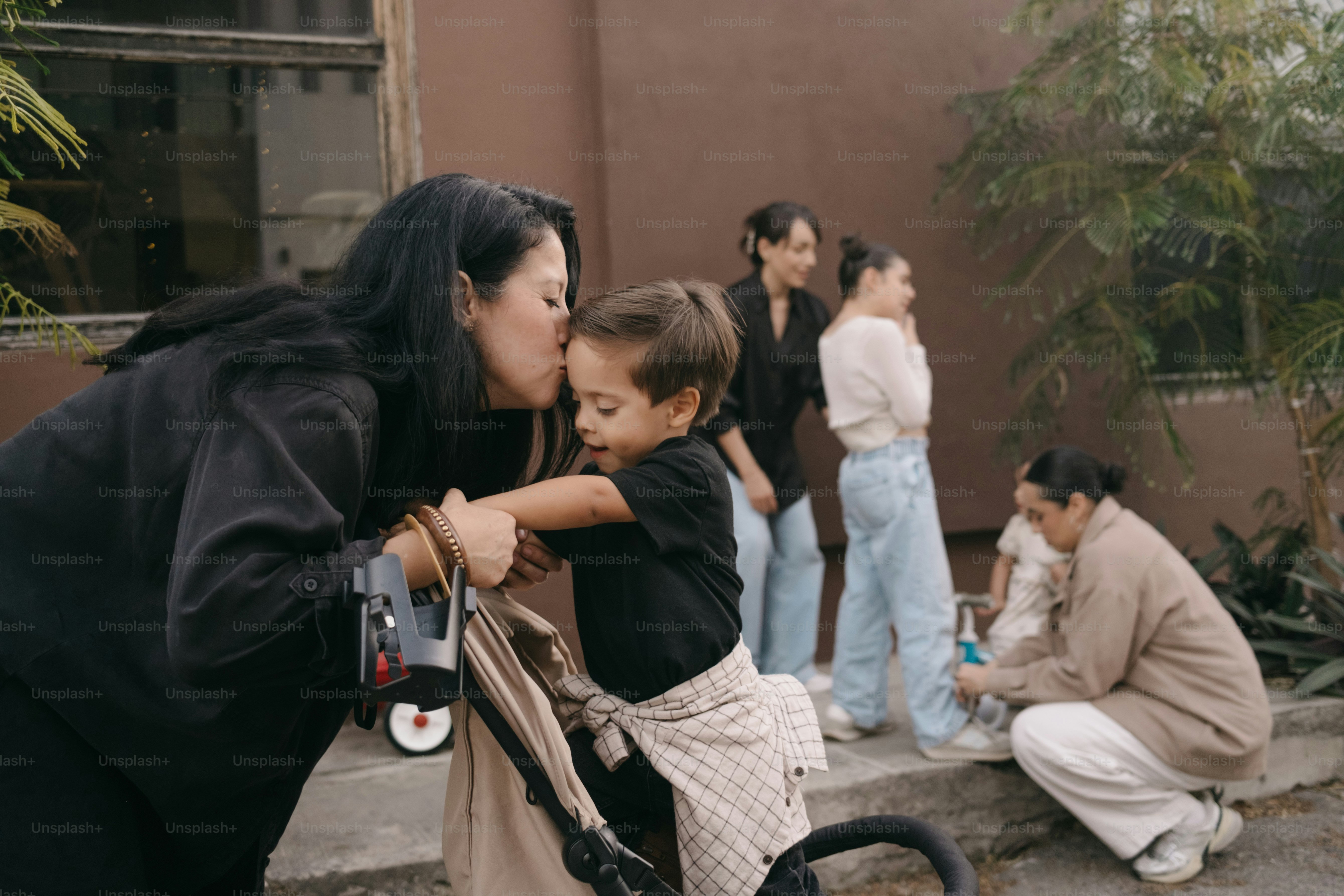 Une femme embrasse un enfant près de la poussette avec la famille en arrière-plan.