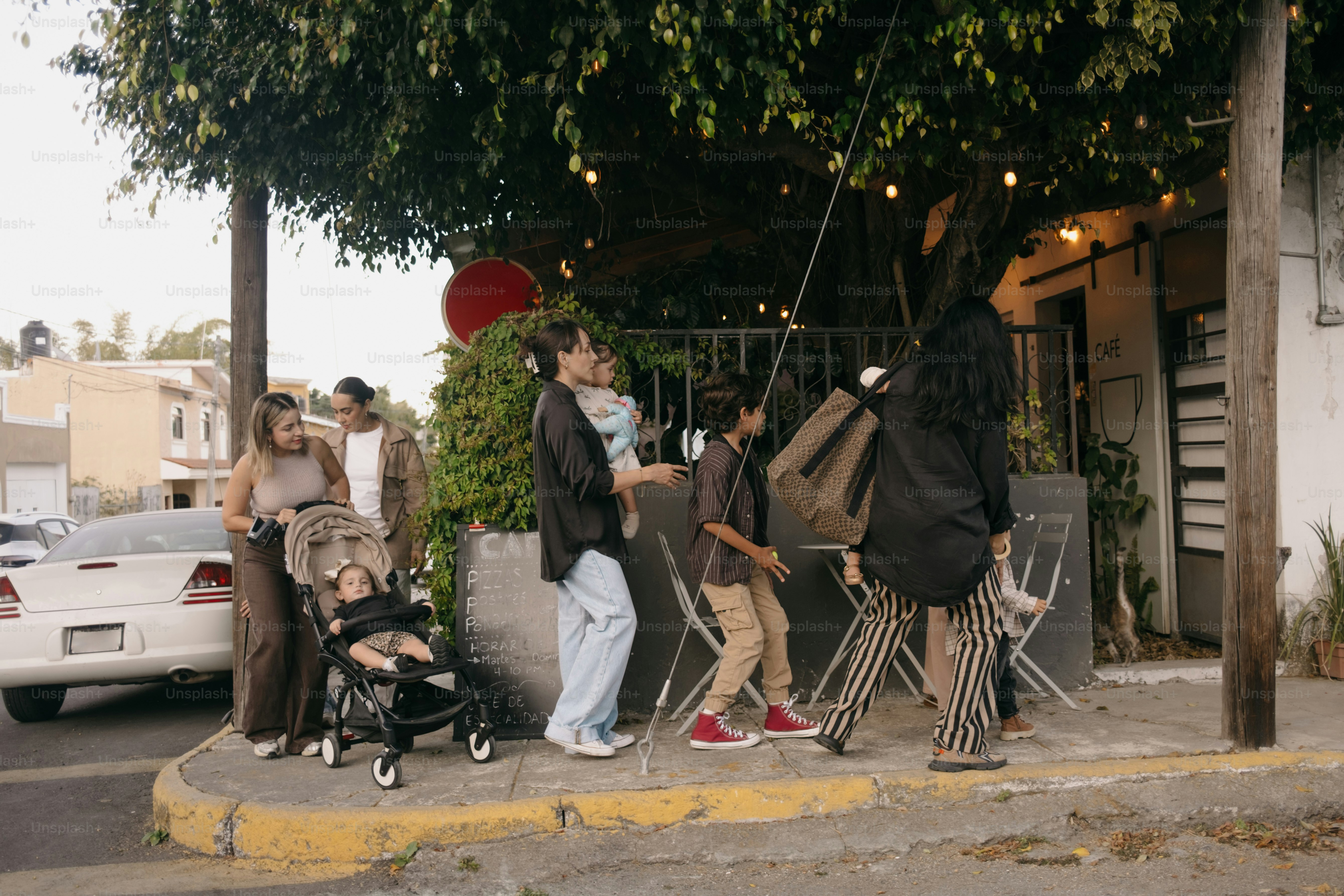 Famille avec poussette passe devant un café en plein air.
