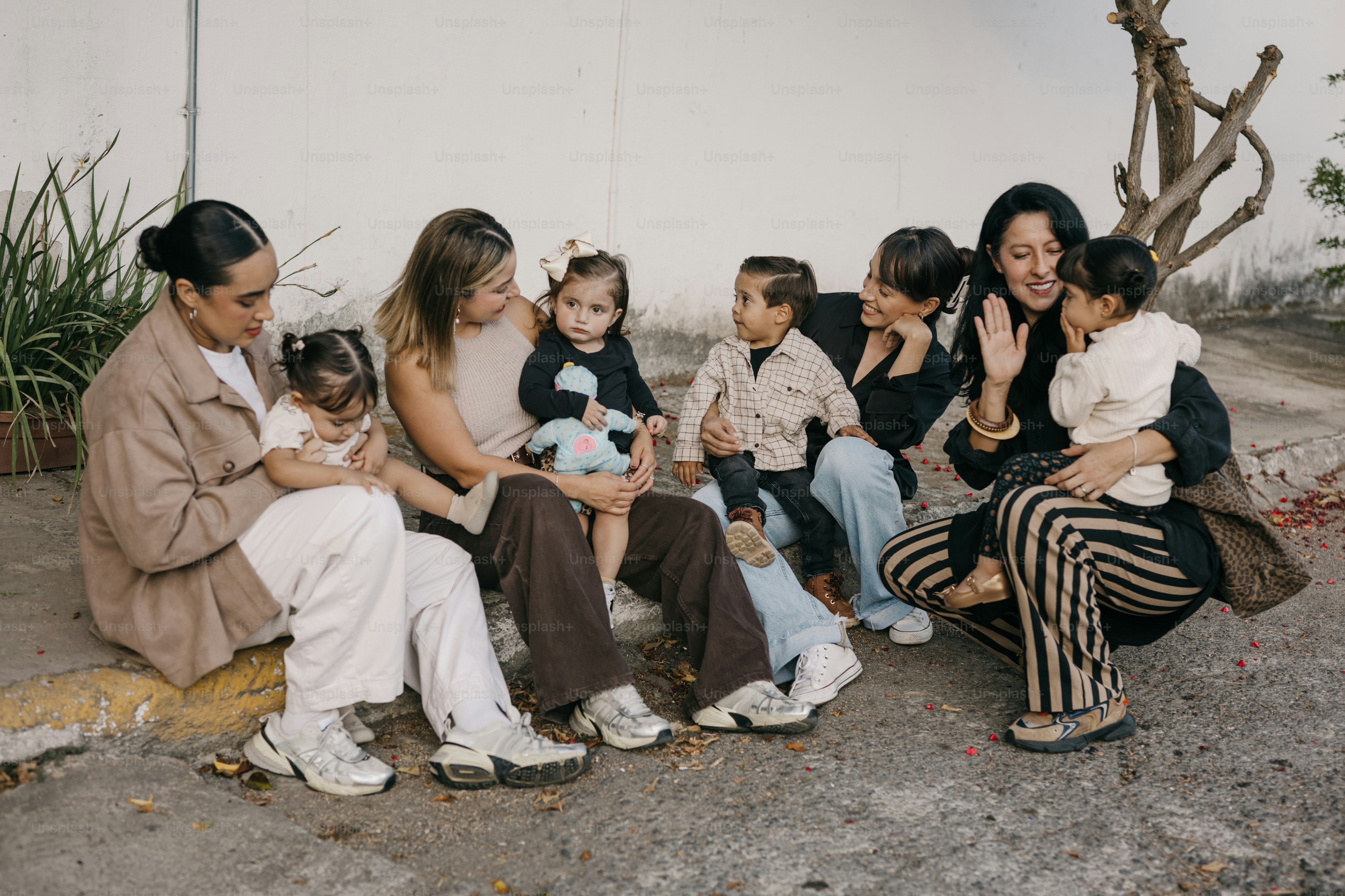 Plusieurs femmes et enfants s’assoient ensemble dehors.