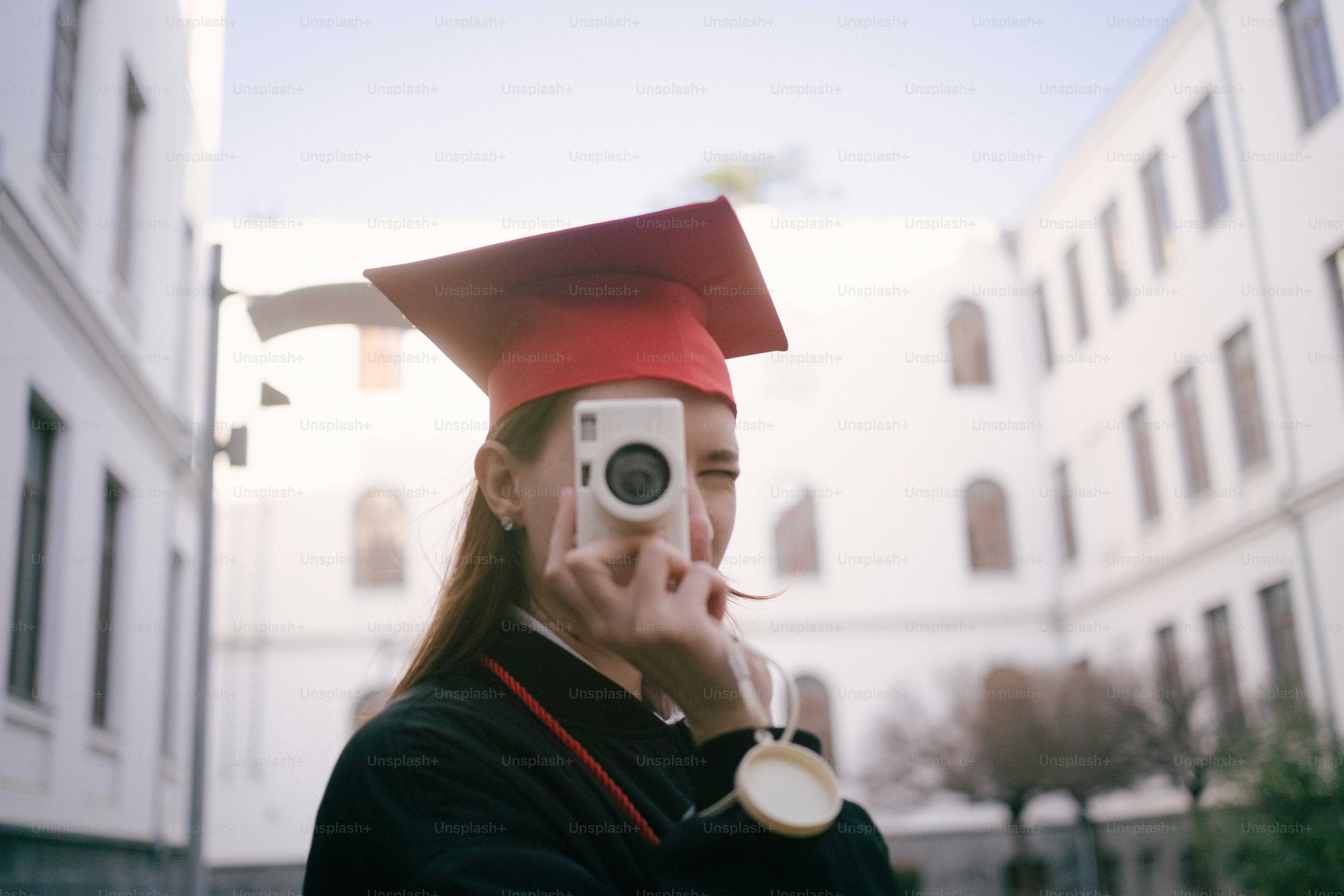 Graduate in cap and gown taking a picture with camera photo – Education ...