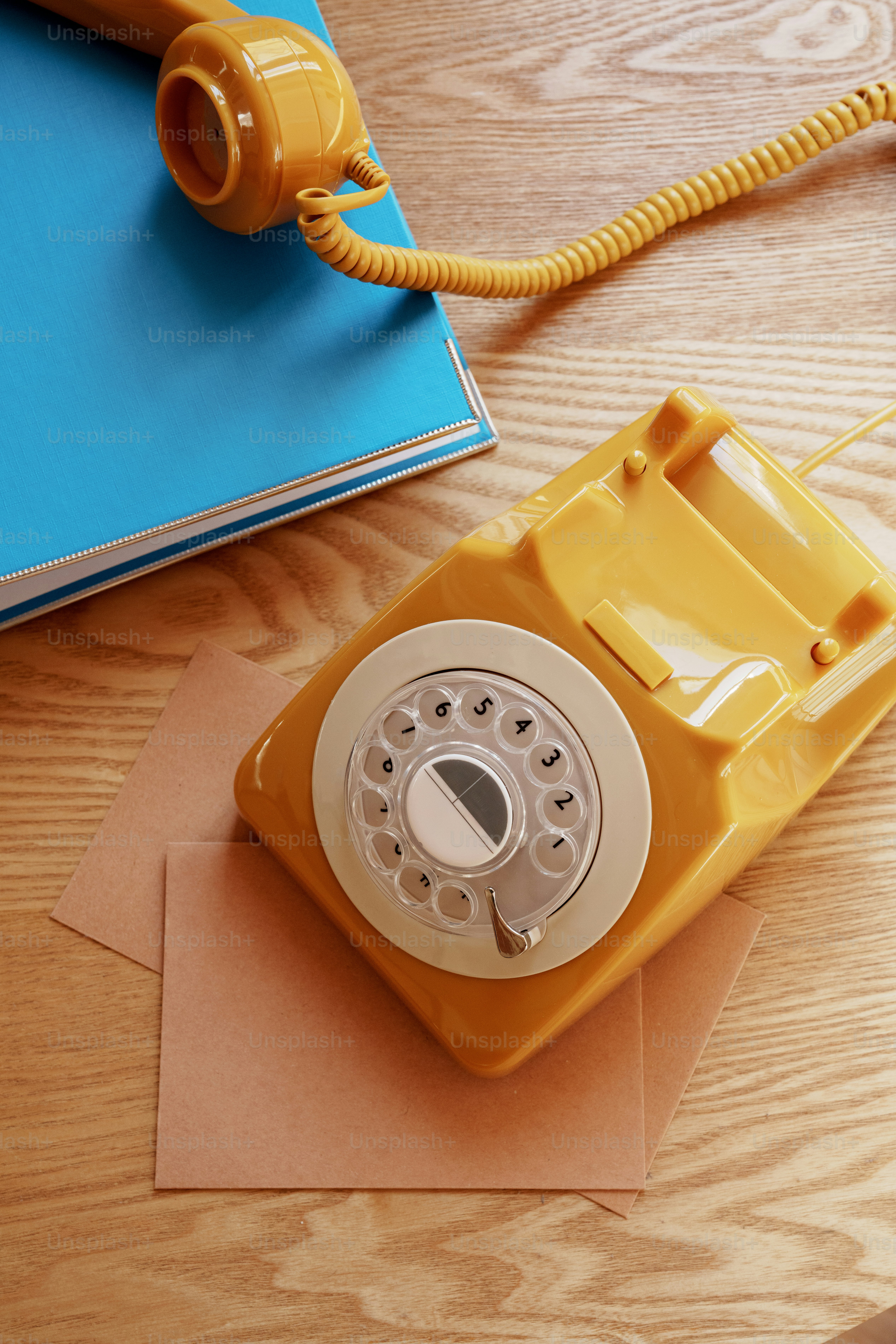 A vintage yellow rotary phone rests on a desk.