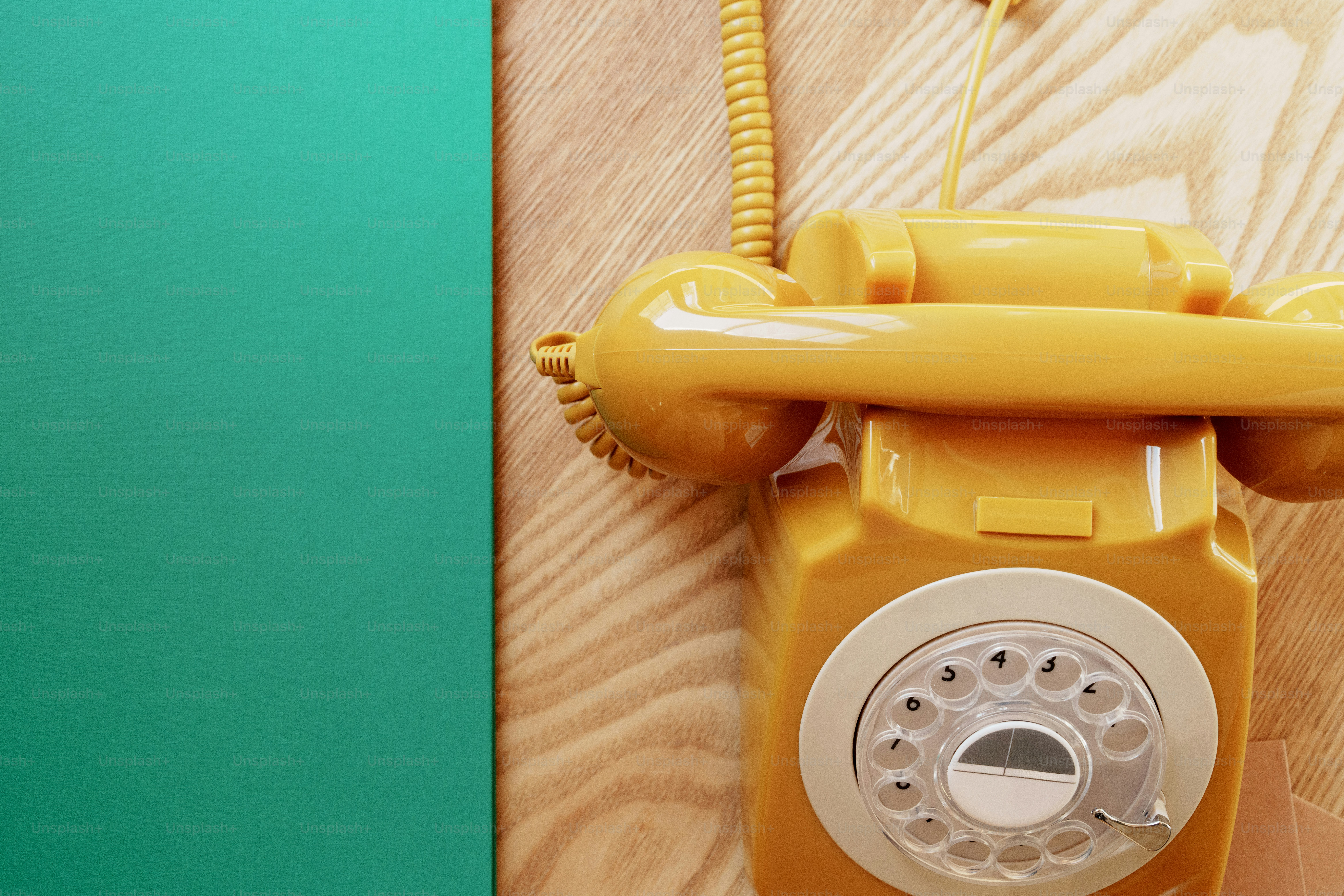 Yellow rotary phone on a wooden wall