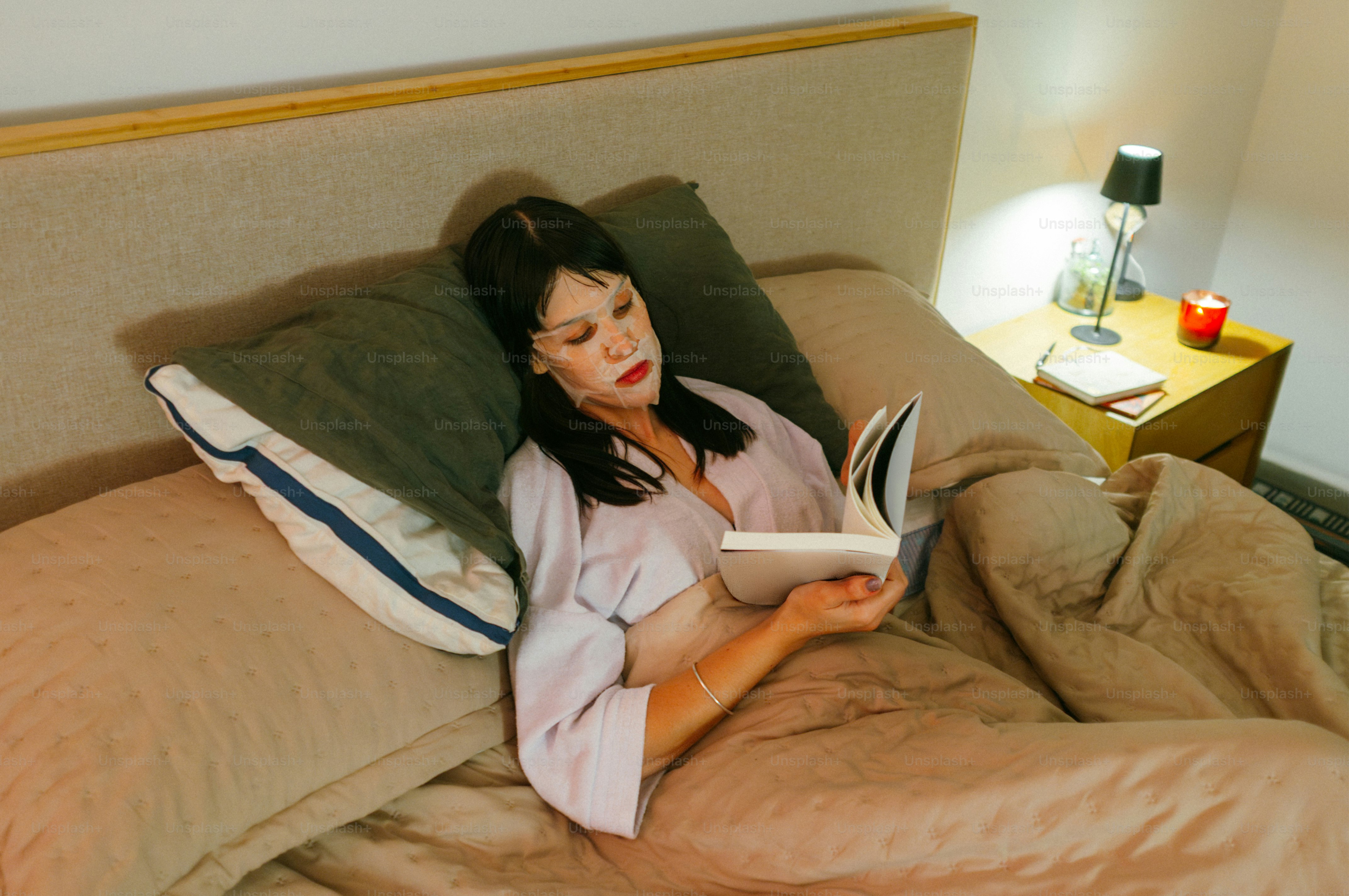 Une femme lisant un livre au lit la nuit.