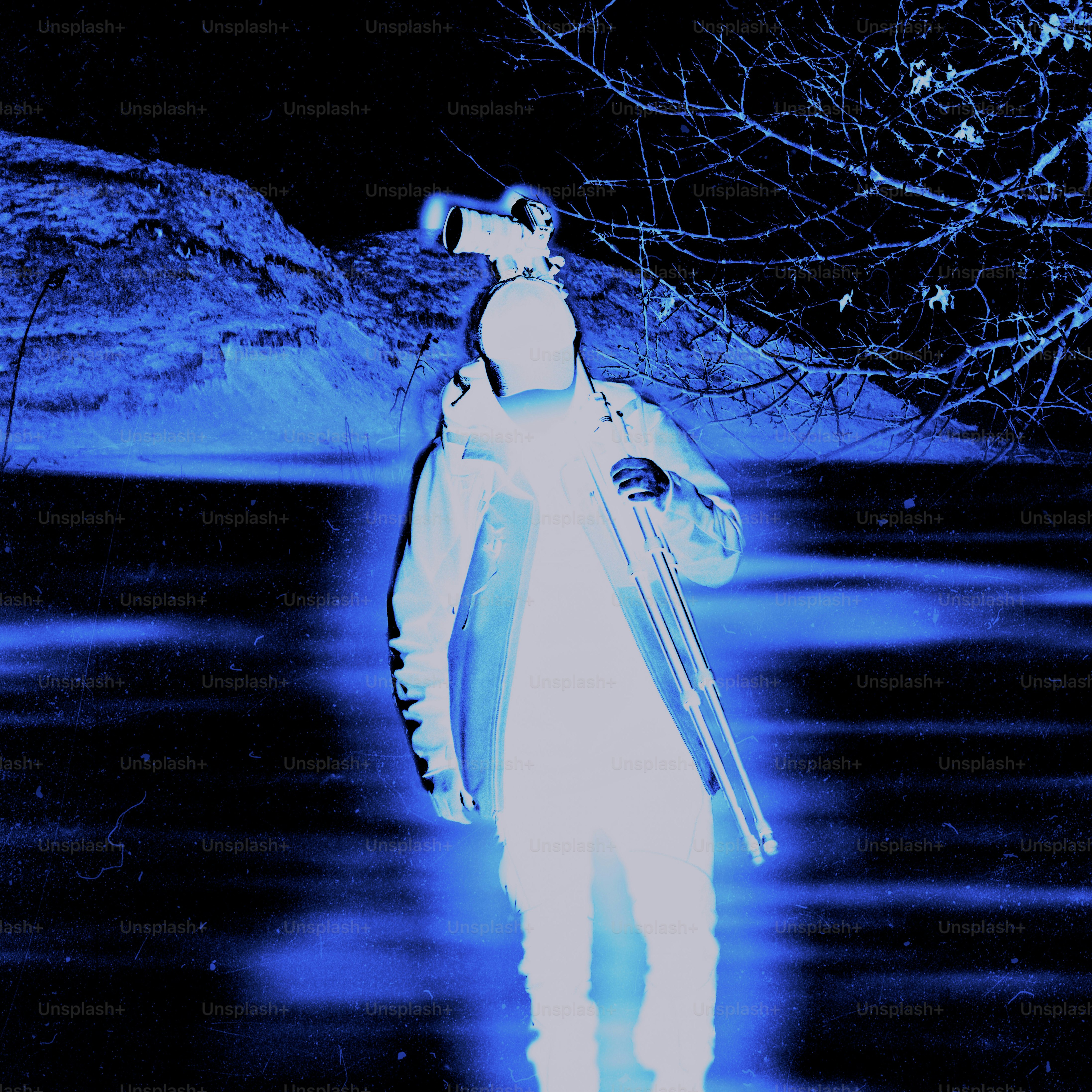 A person holding a camera and tripod in the dark.
