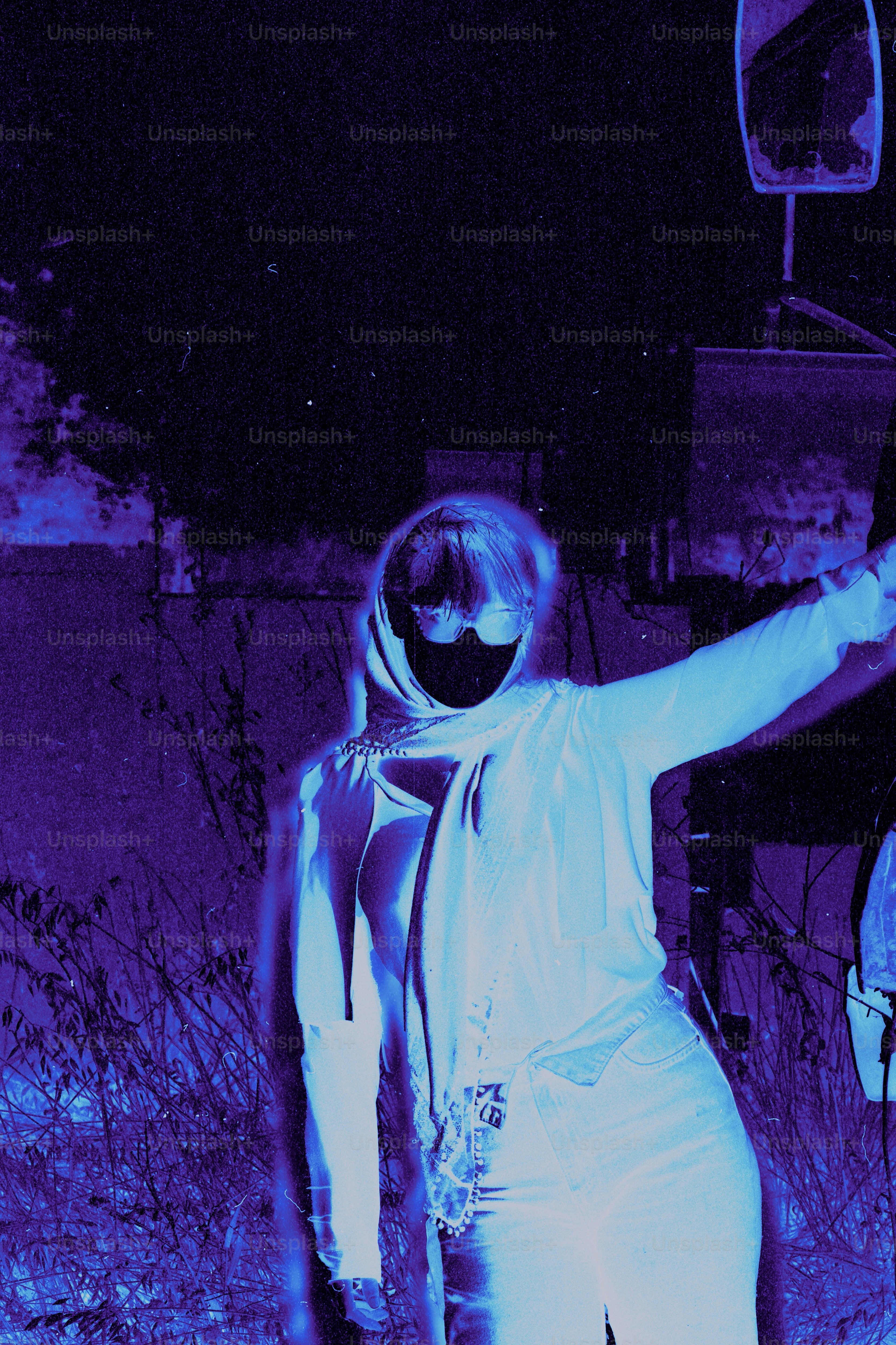 A person in a headscarf and sunglasses at night