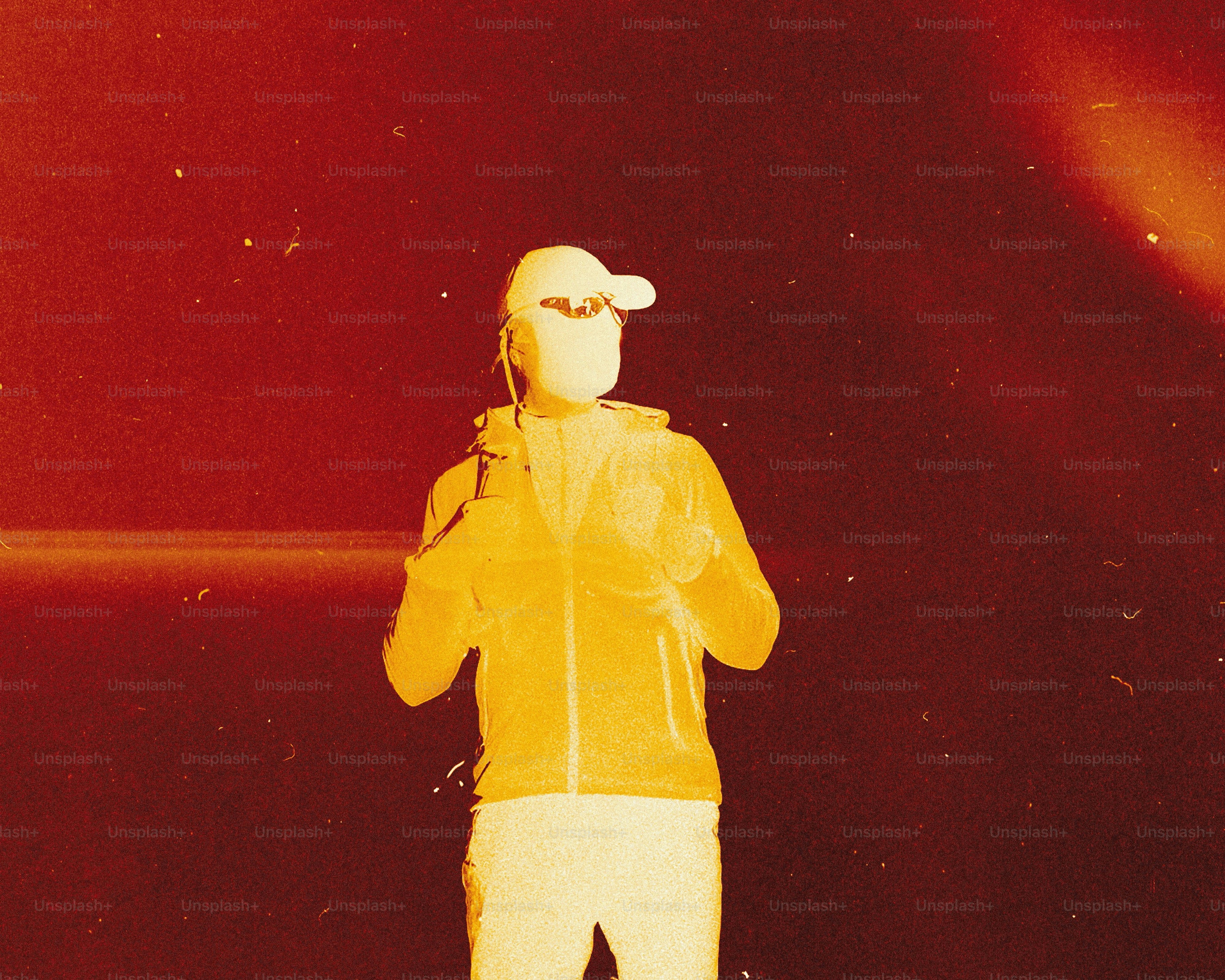 Person wearing a cap and jacket, viewed with thermal imaging.
