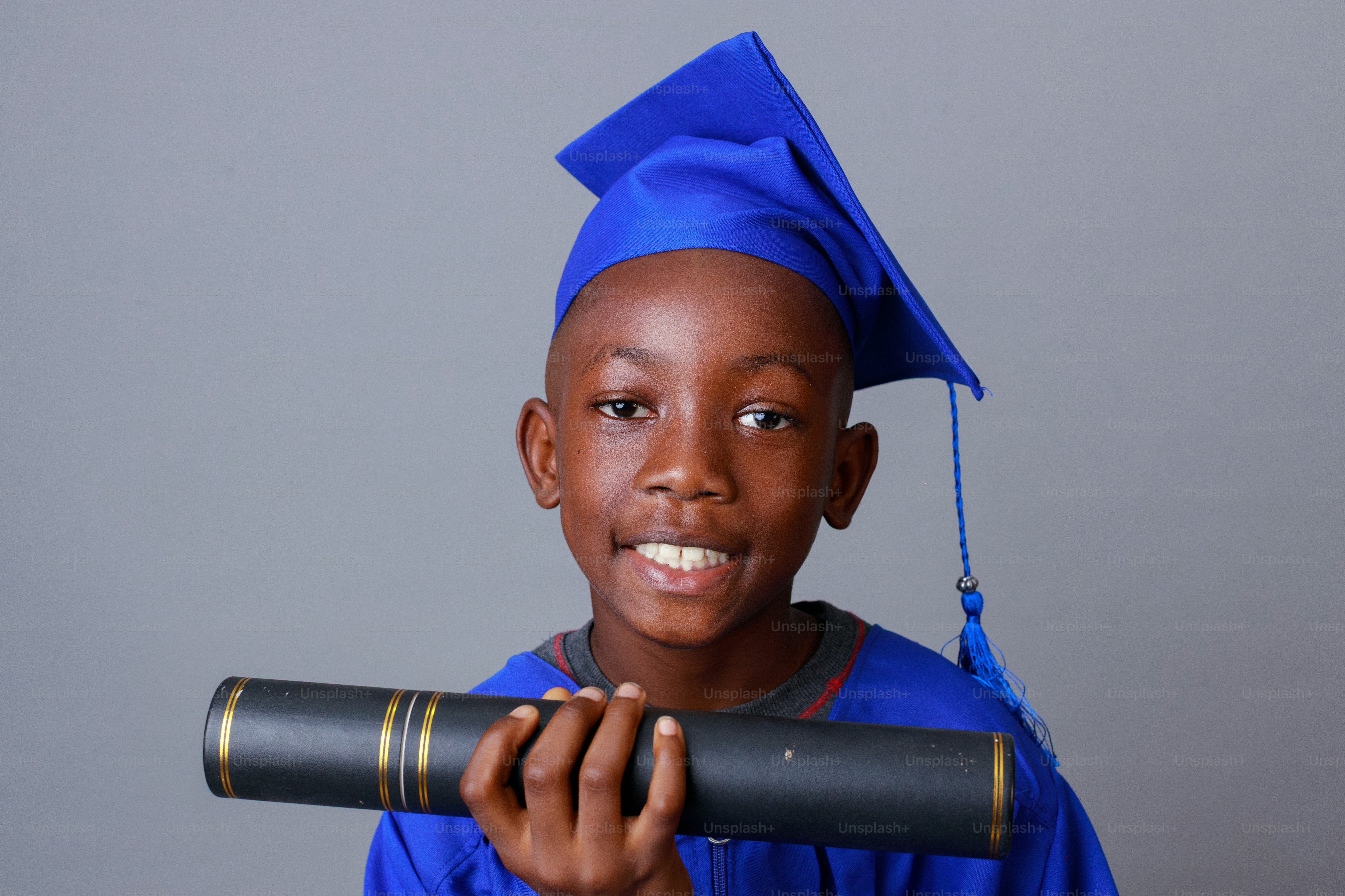Young boy in a graduation cap holding his diploma