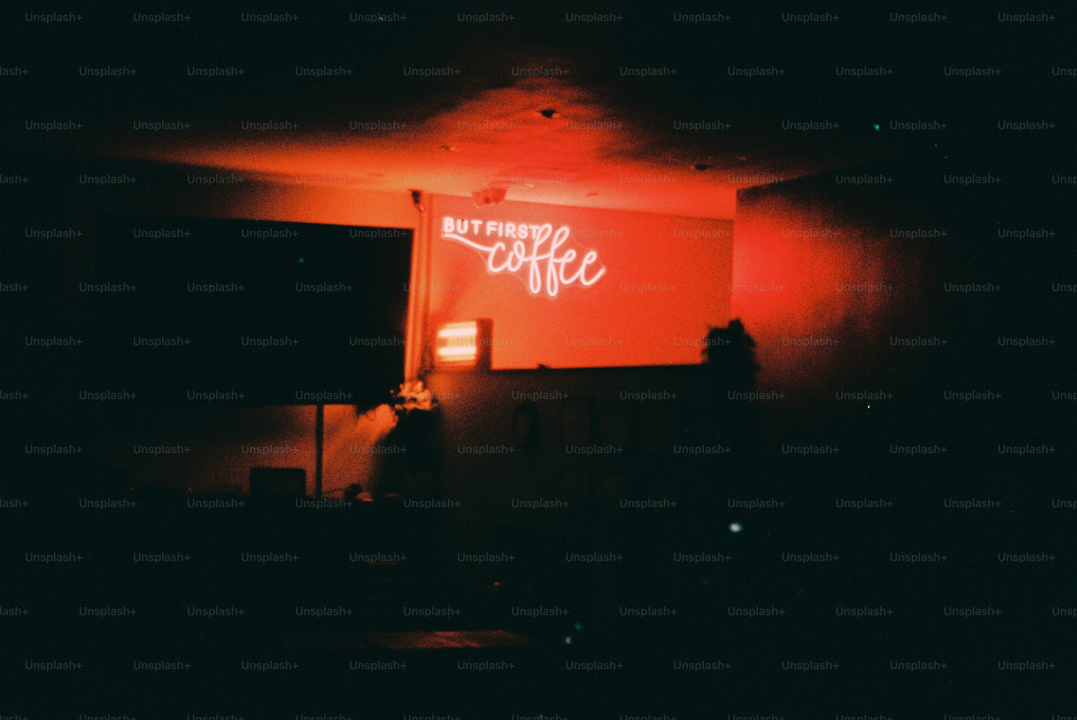 Cartel de neón que dice "pero primero, café" brilla en rojo